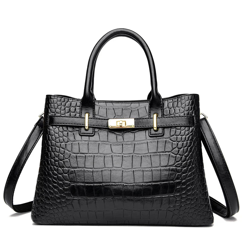 Black crocodile-patterned handbag with gold hardware on a white background