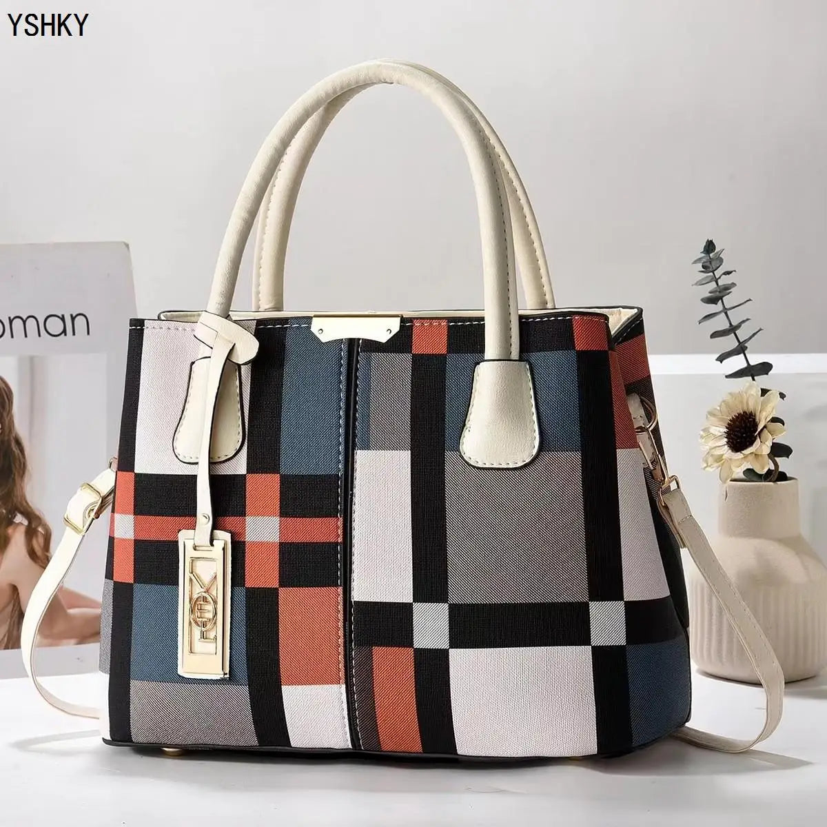 Multicolored checkered handbag with beige handles on a white surface