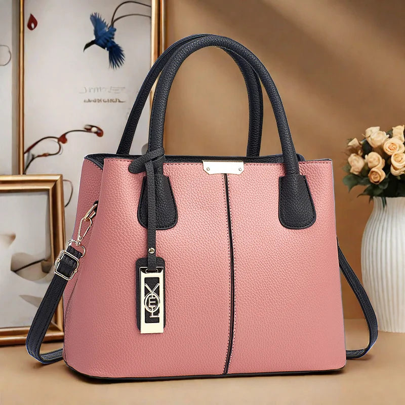 Pink handbag with black accents on a beige surface