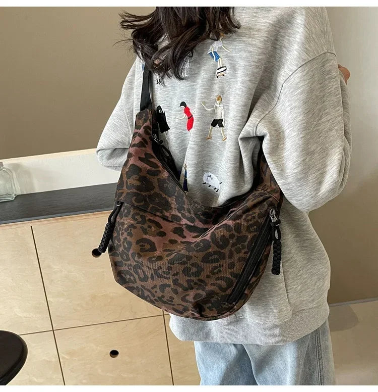 Person wearing a gray sweatshirt with a leopard print bag over their shoulder indoors.