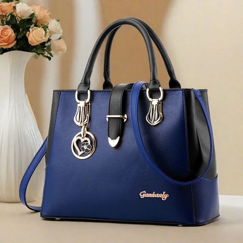 Blue handbag with black accents and gold hardware on a beige background