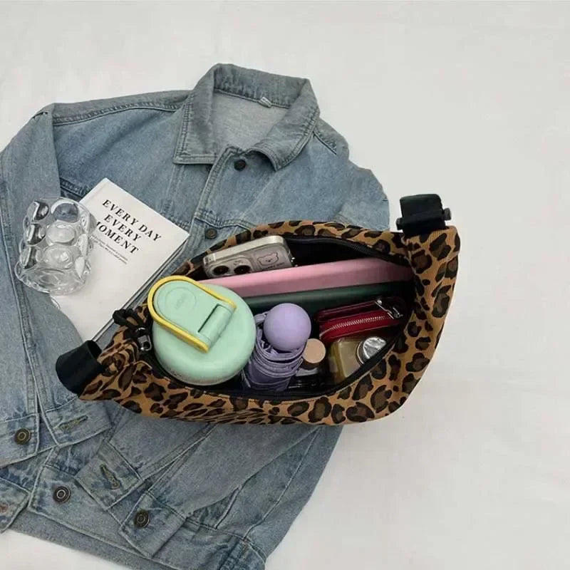 Leopard print fanny pack with various items on a denim jacket against a white background