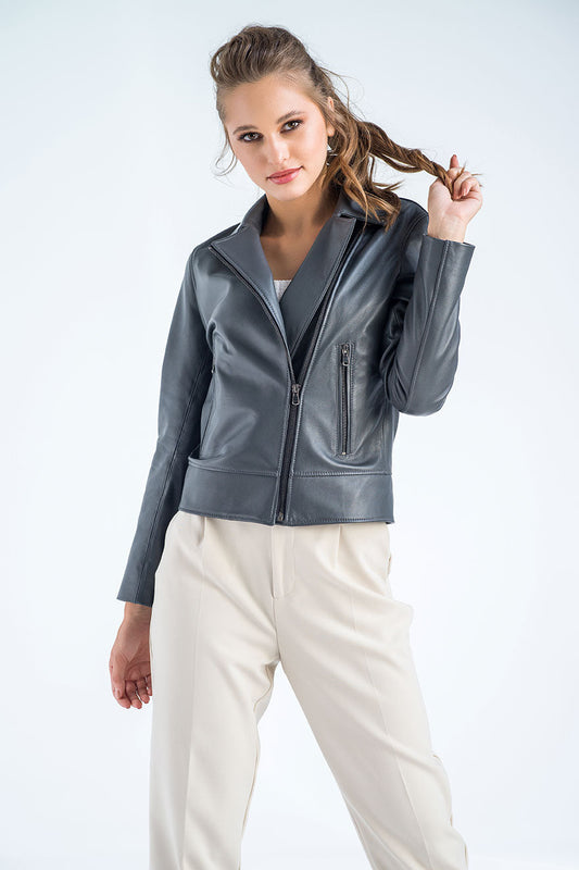 Woman wearing a gray leather jacket and white pants on a light gray background