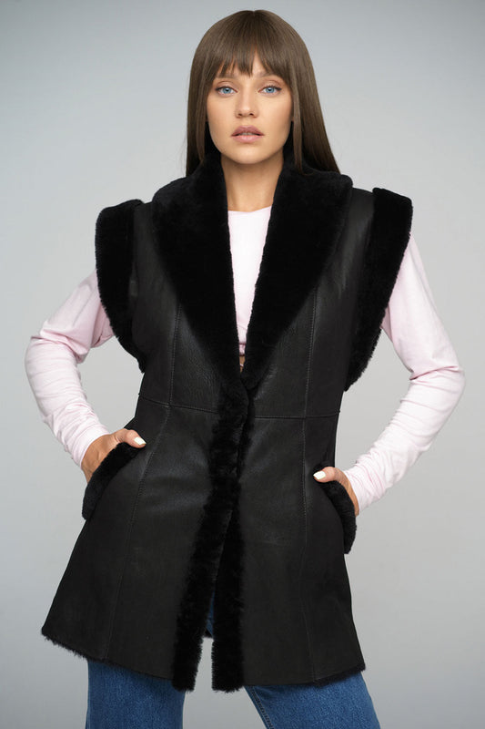 Woman wearing a black vest with fur trim on a gray background