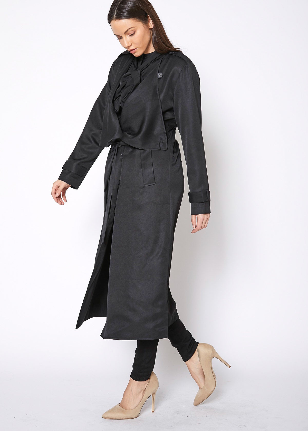 Woman wearing a long black coat on a white background