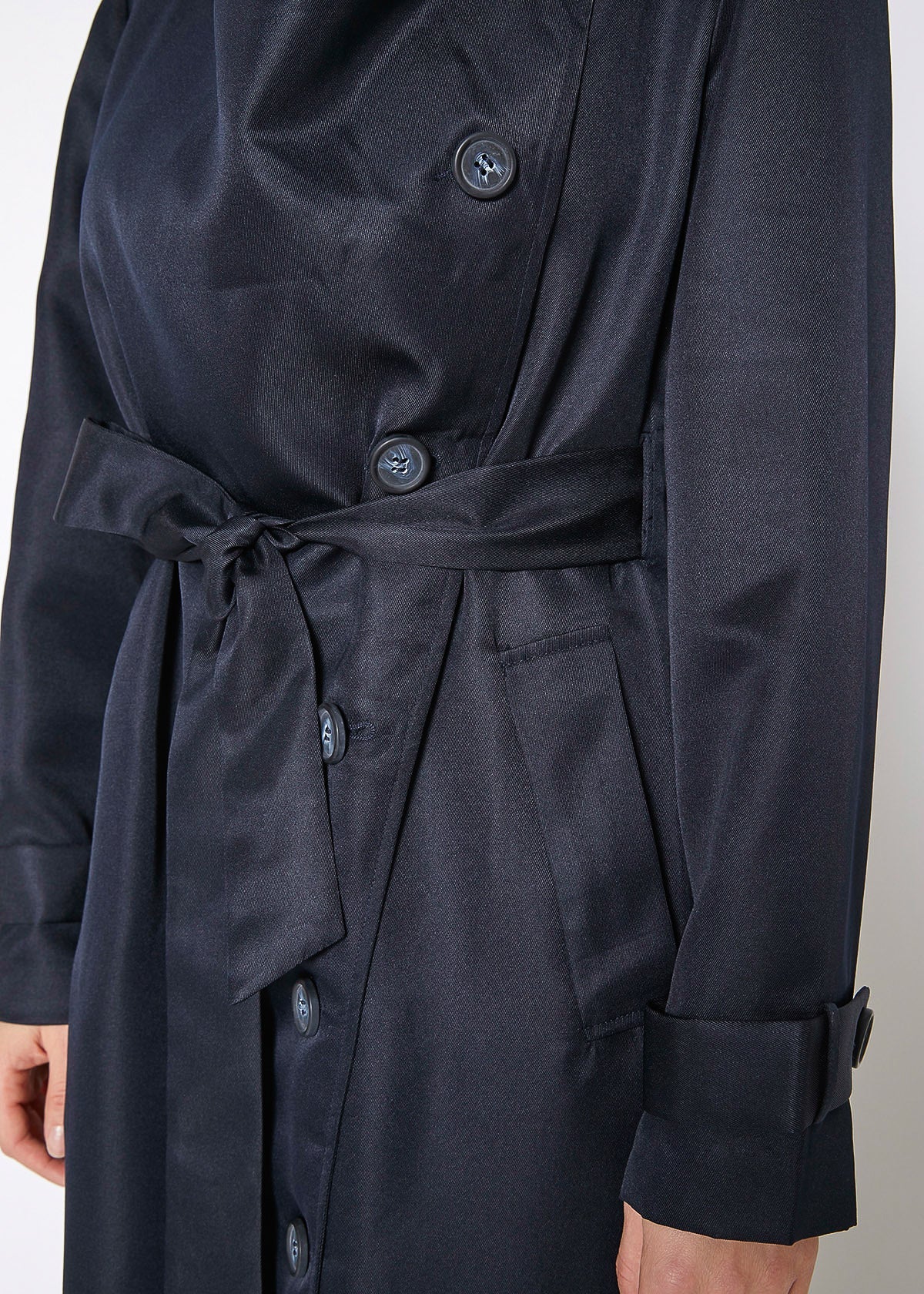 Navy blue trench coat with buttons on a neutral background