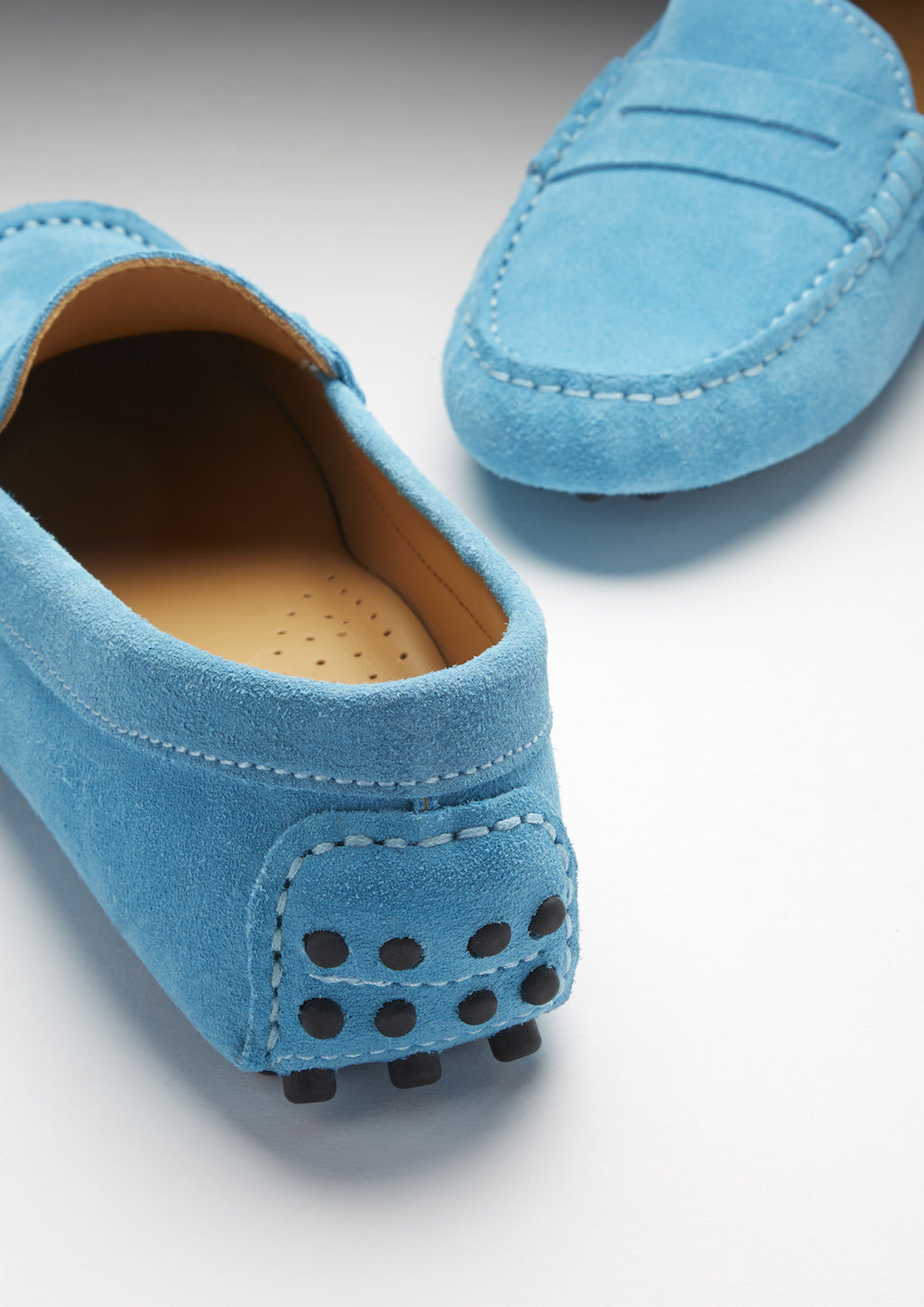 Pair of blue suede loafers on a light gray background