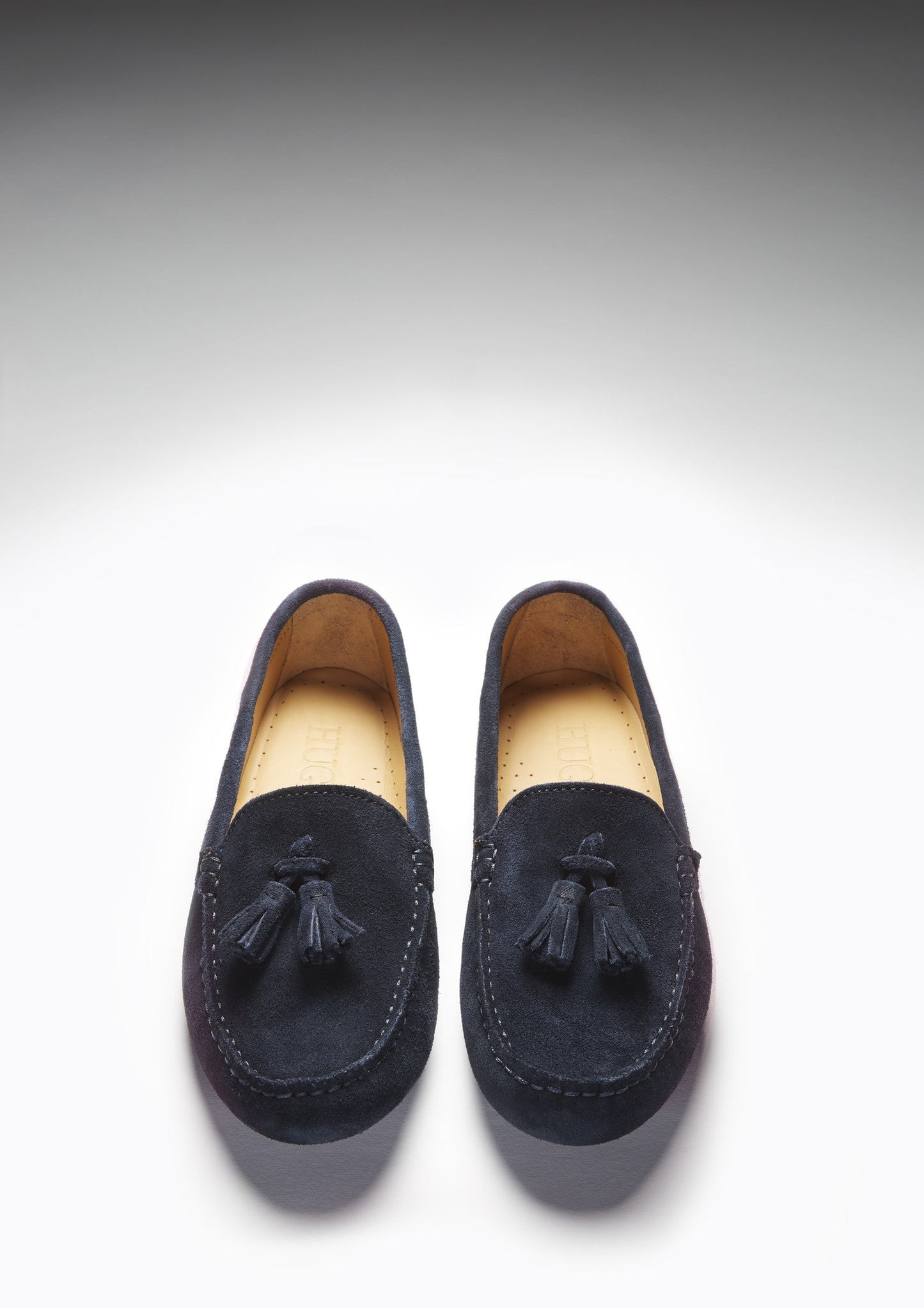 Pair of navy loafers with tassels on a light gray background