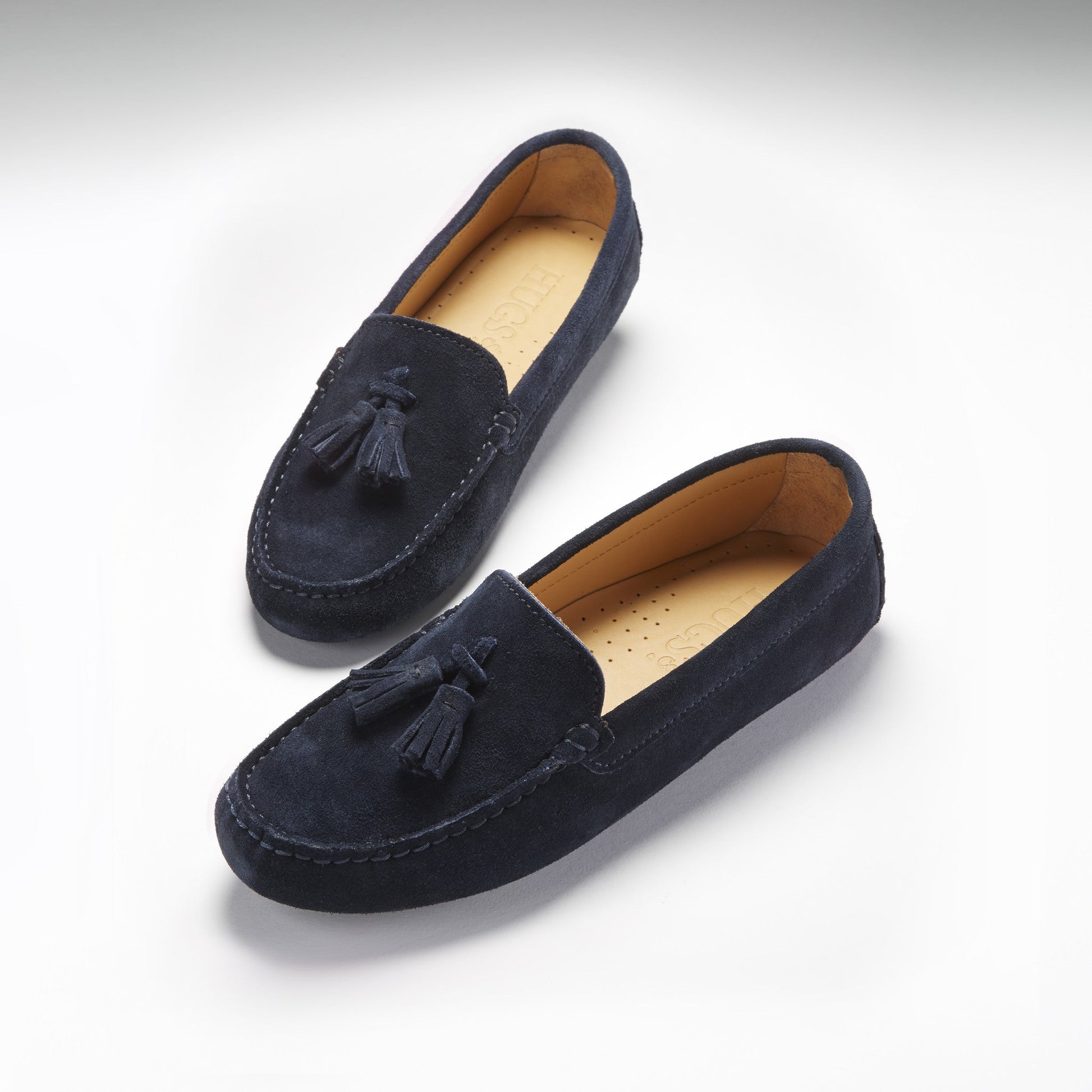 Pair of navy blue loafers with tassels on a light gray background