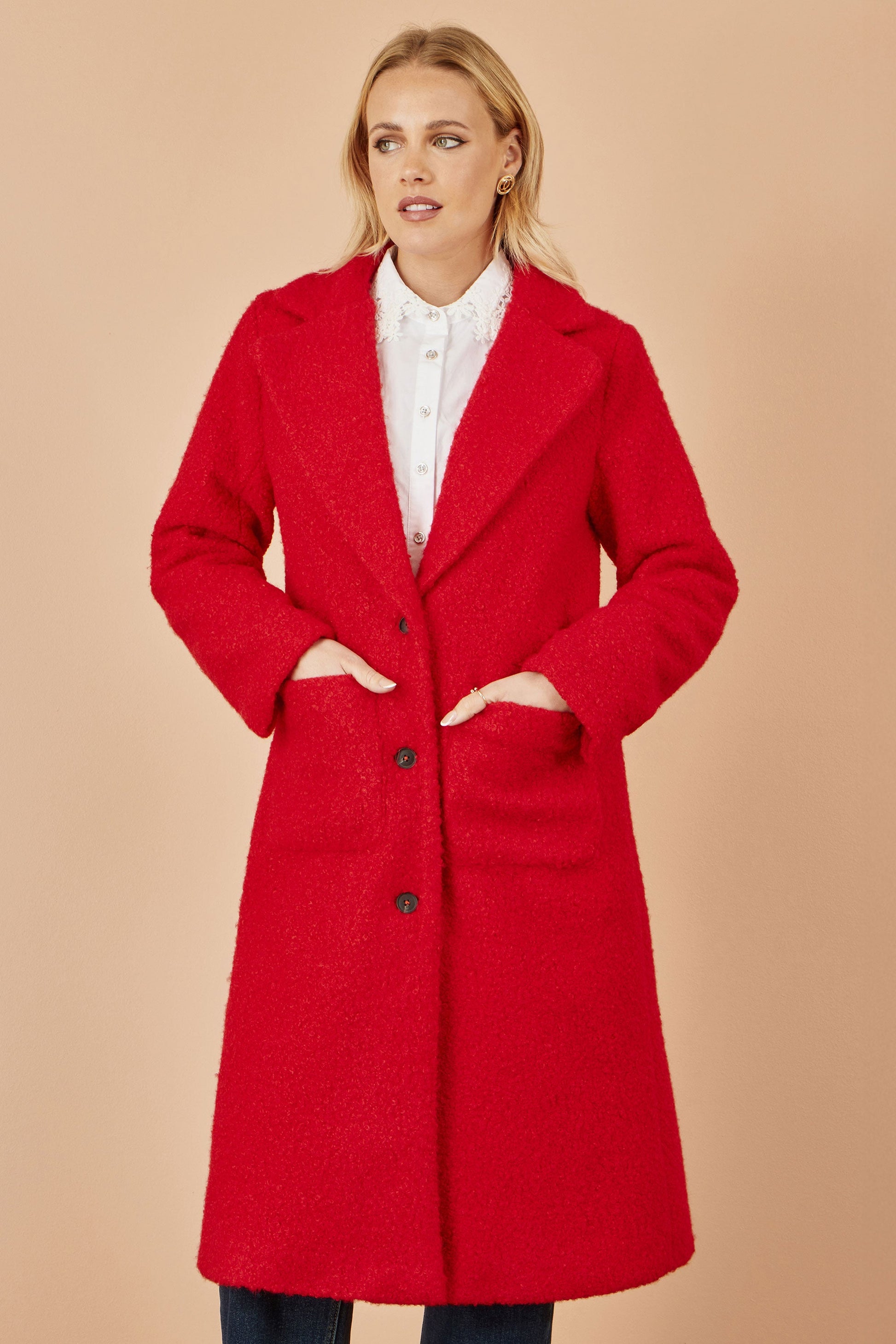 Woman wearing a red coat against a beige background
