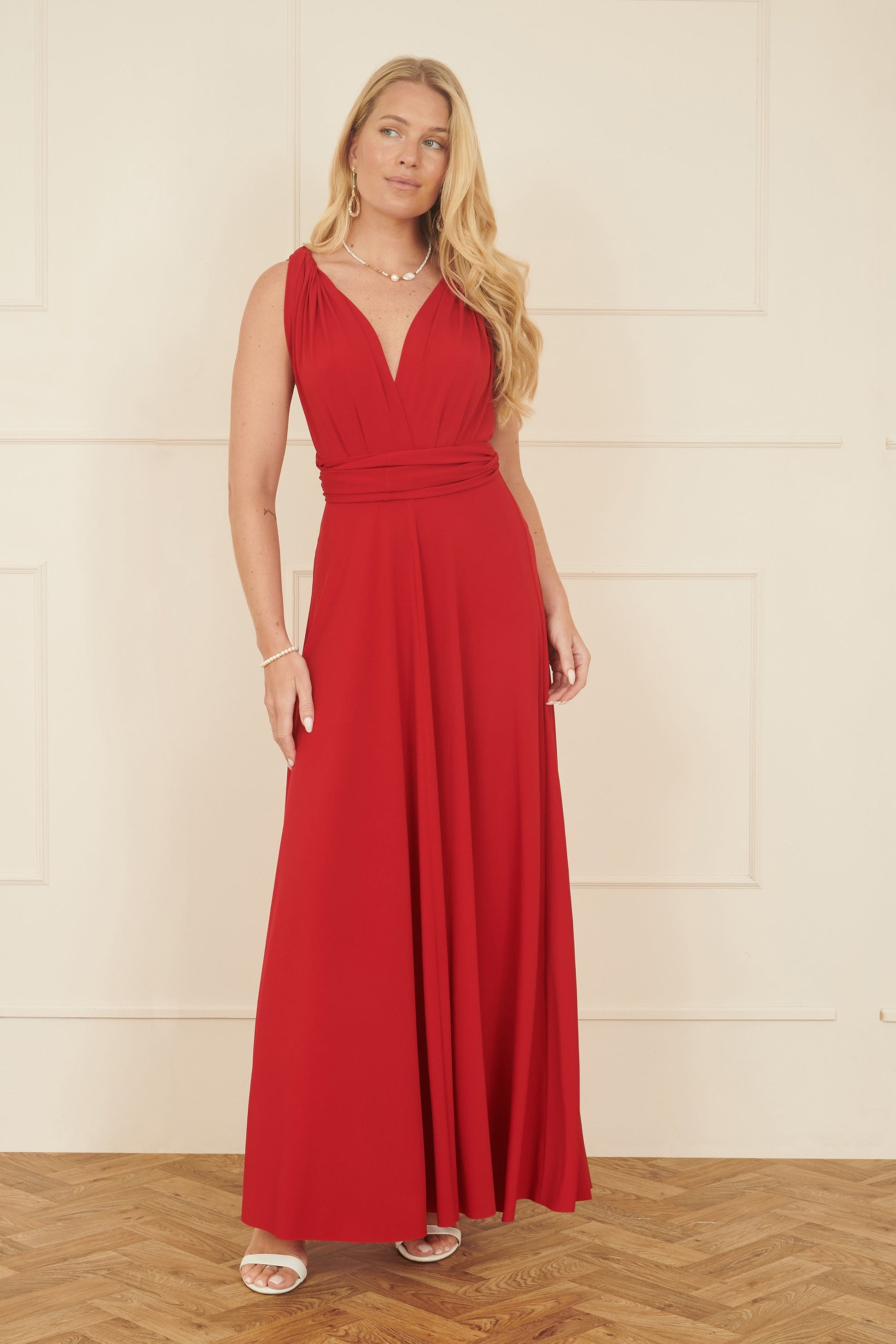 Woman wearing a red dress standing against a white wall.