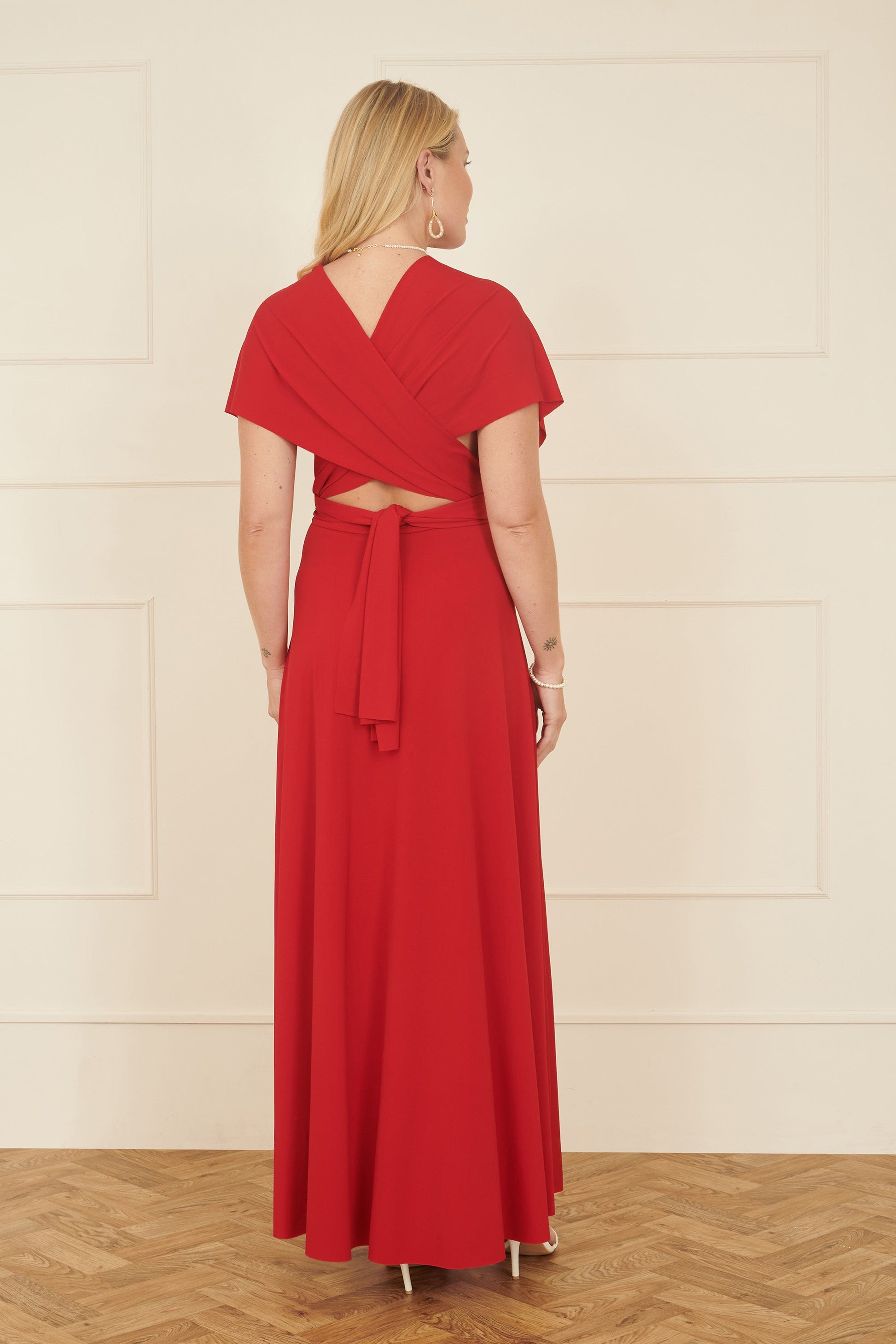 Woman wearing a red dress with a white wall background