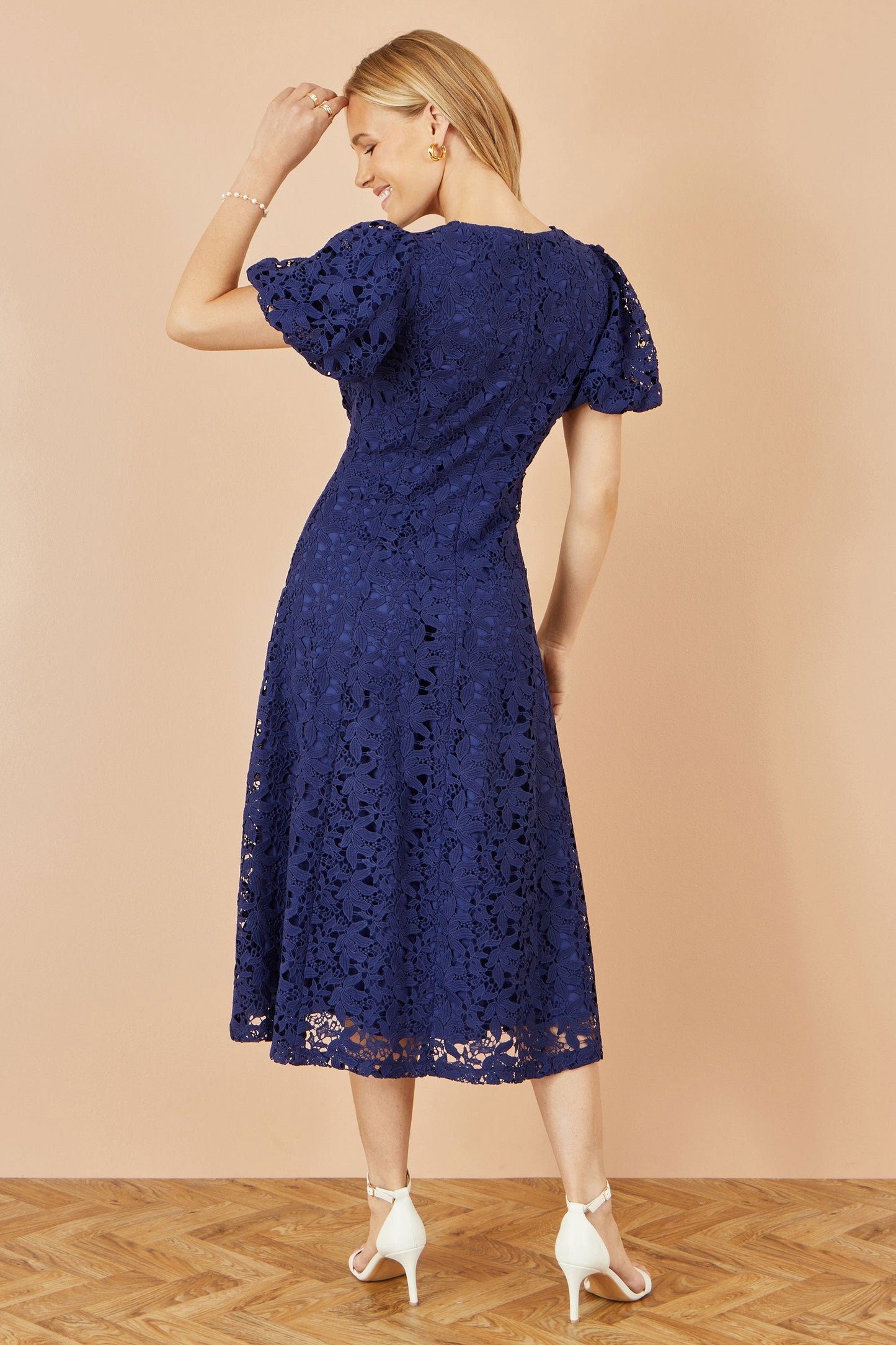 Woman wearing a blue lace dress against a beige background