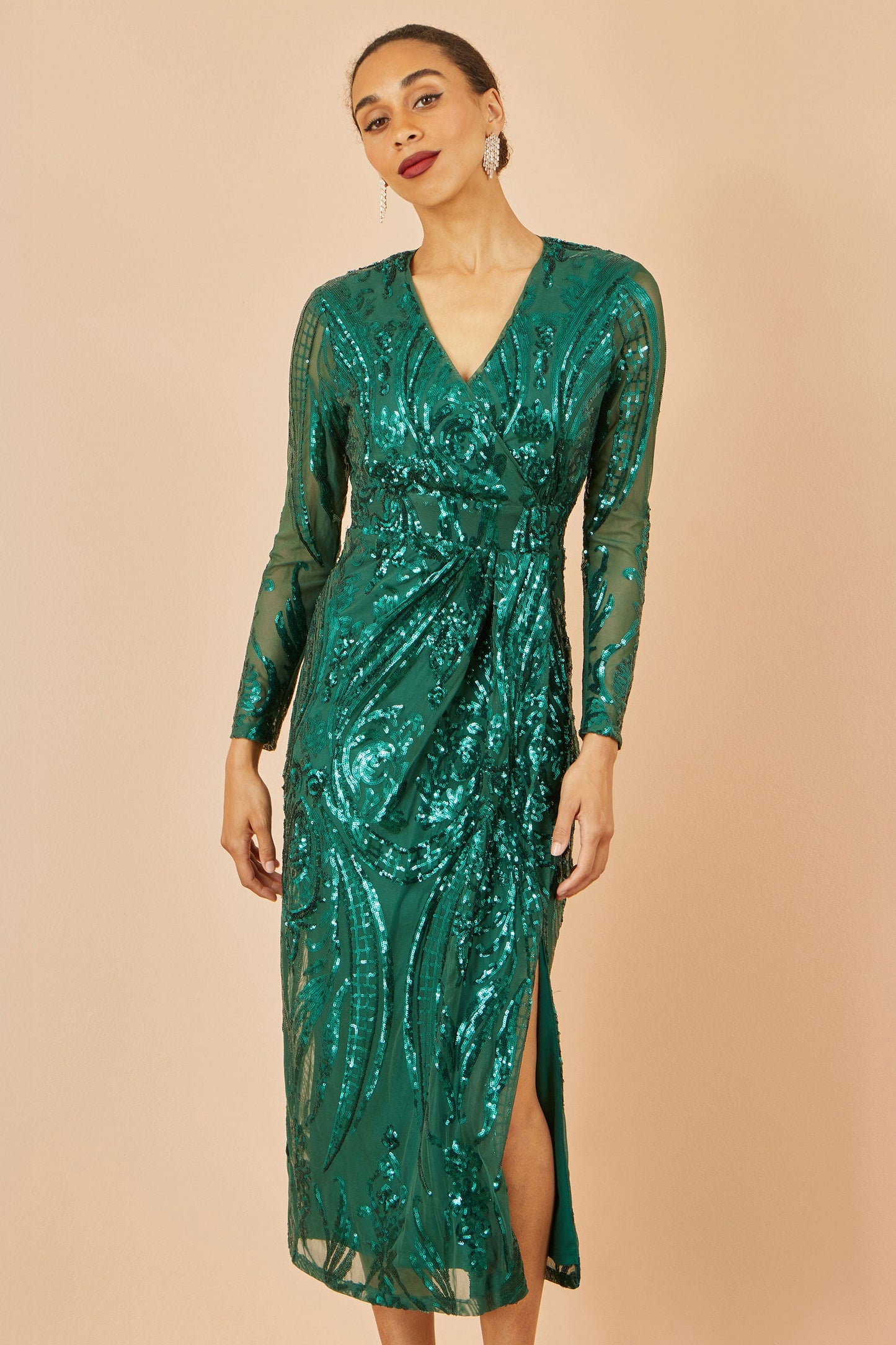 Woman wearing a green sequin dress against a beige background