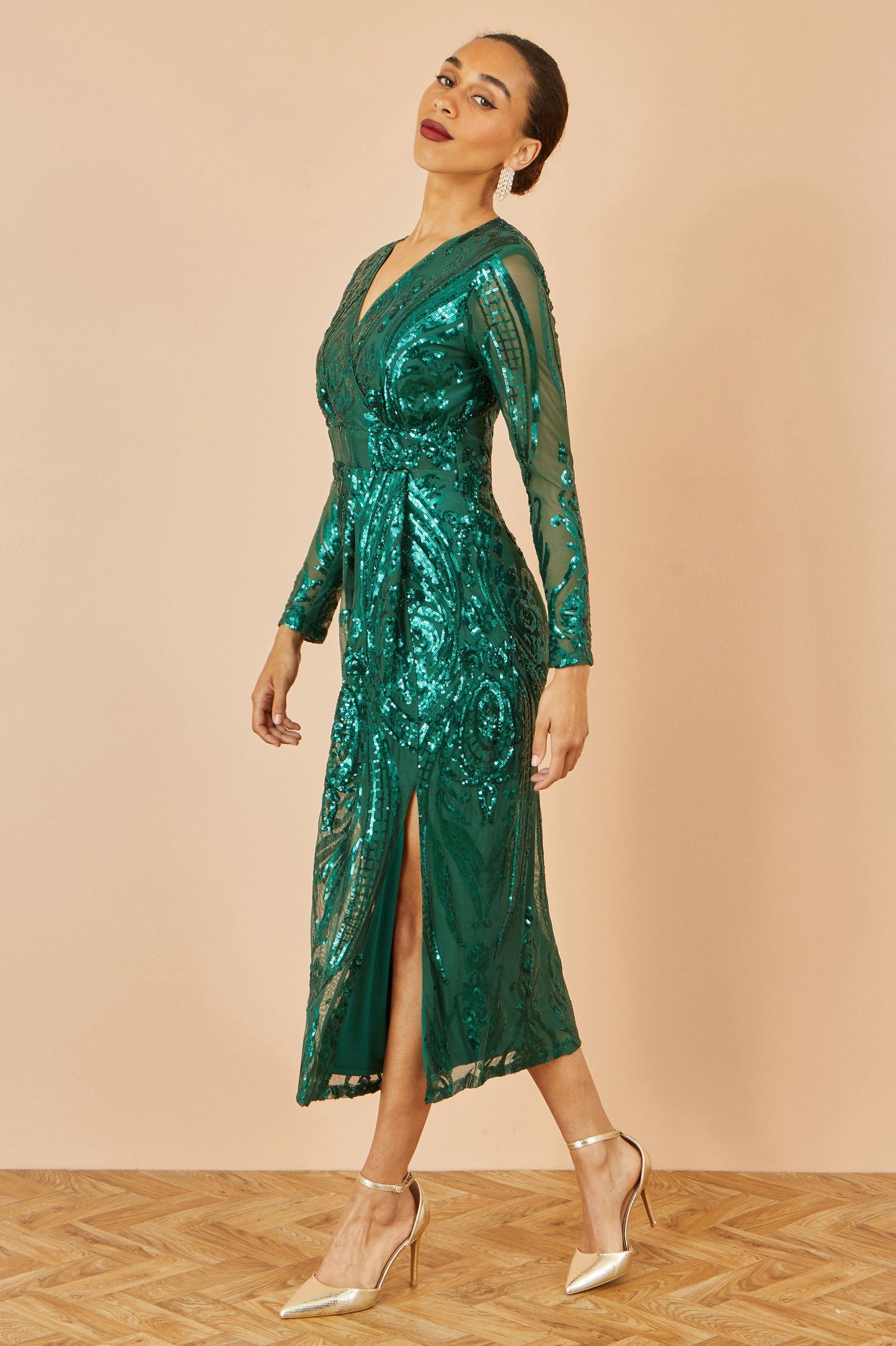 Woman wearing a green sequin dress against a beige background