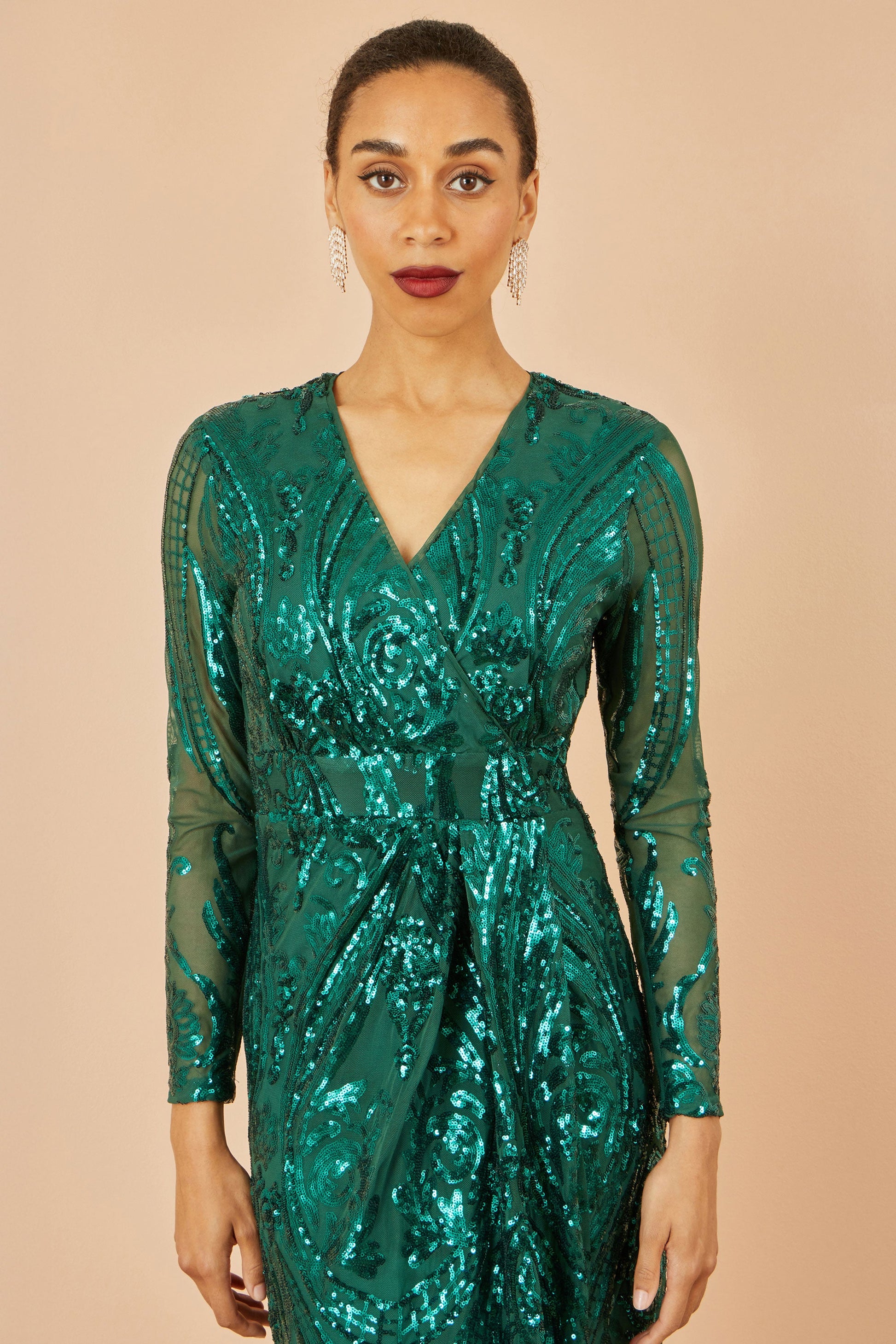 Woman wearing a green sequin dress against a beige background