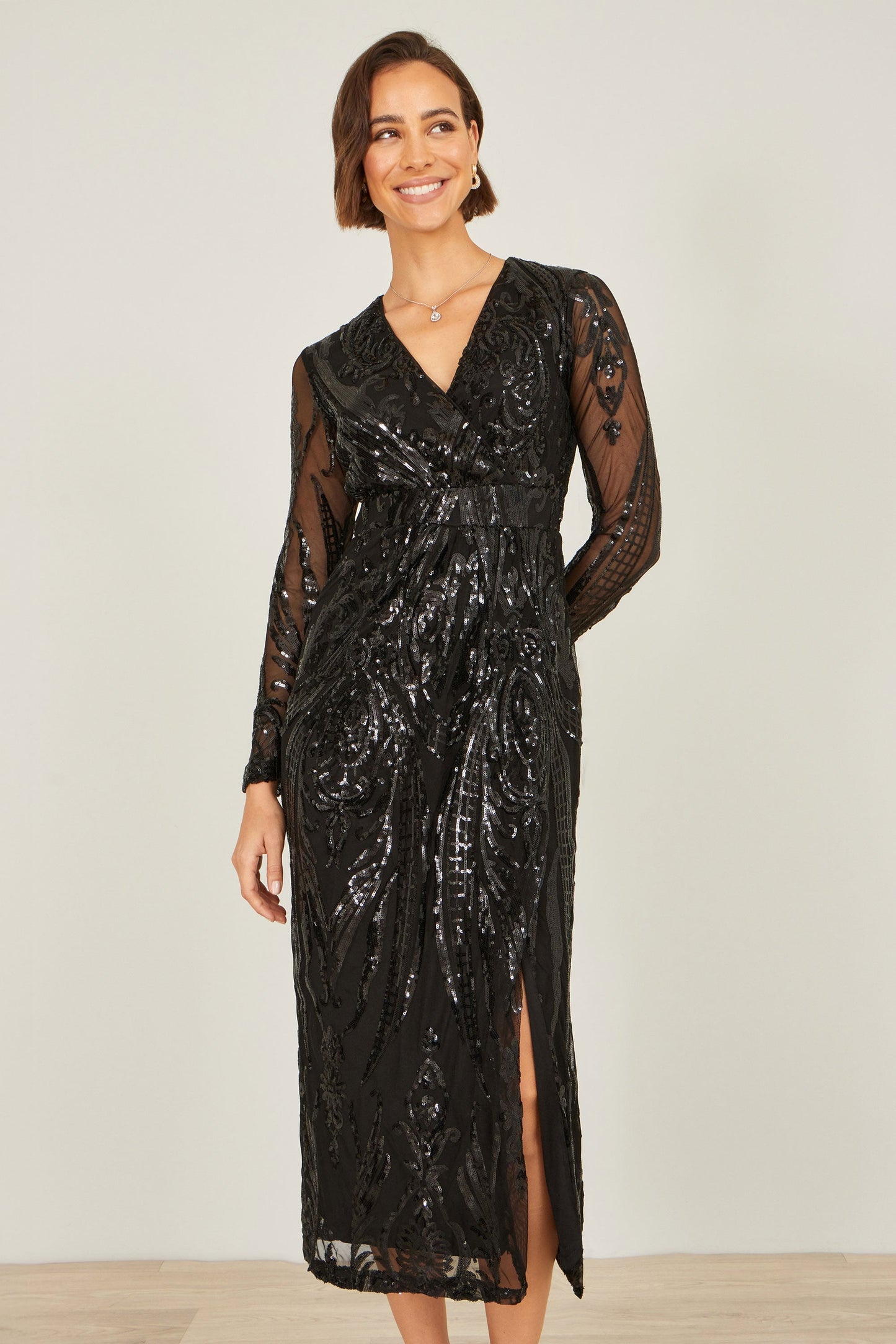 Woman wearing a black sequin dress against a plain background