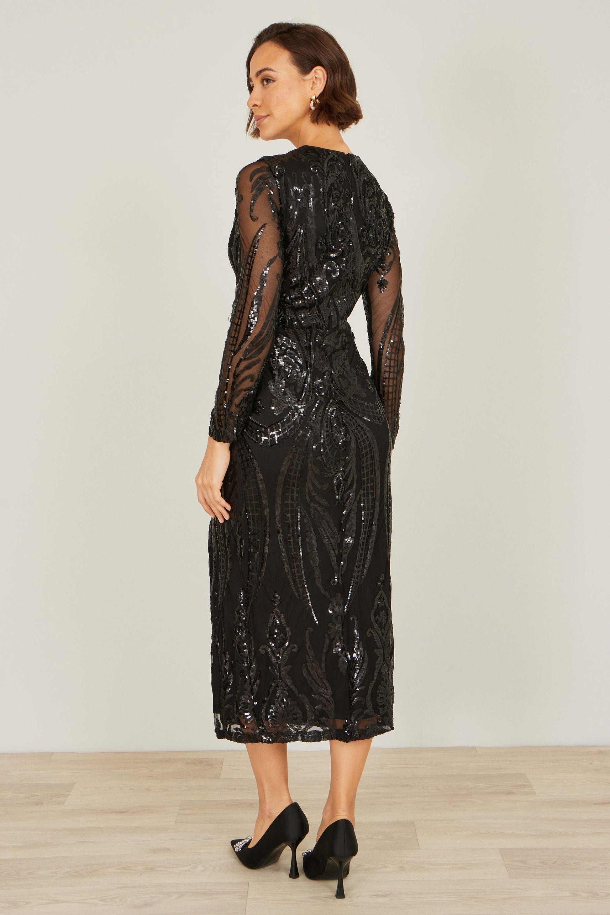 Woman wearing a black sequin dress against a white background