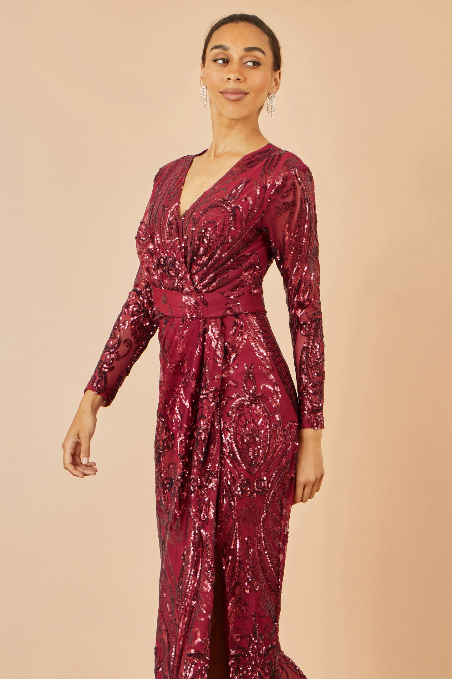 Woman wearing a burgundy sequin dress against a beige background