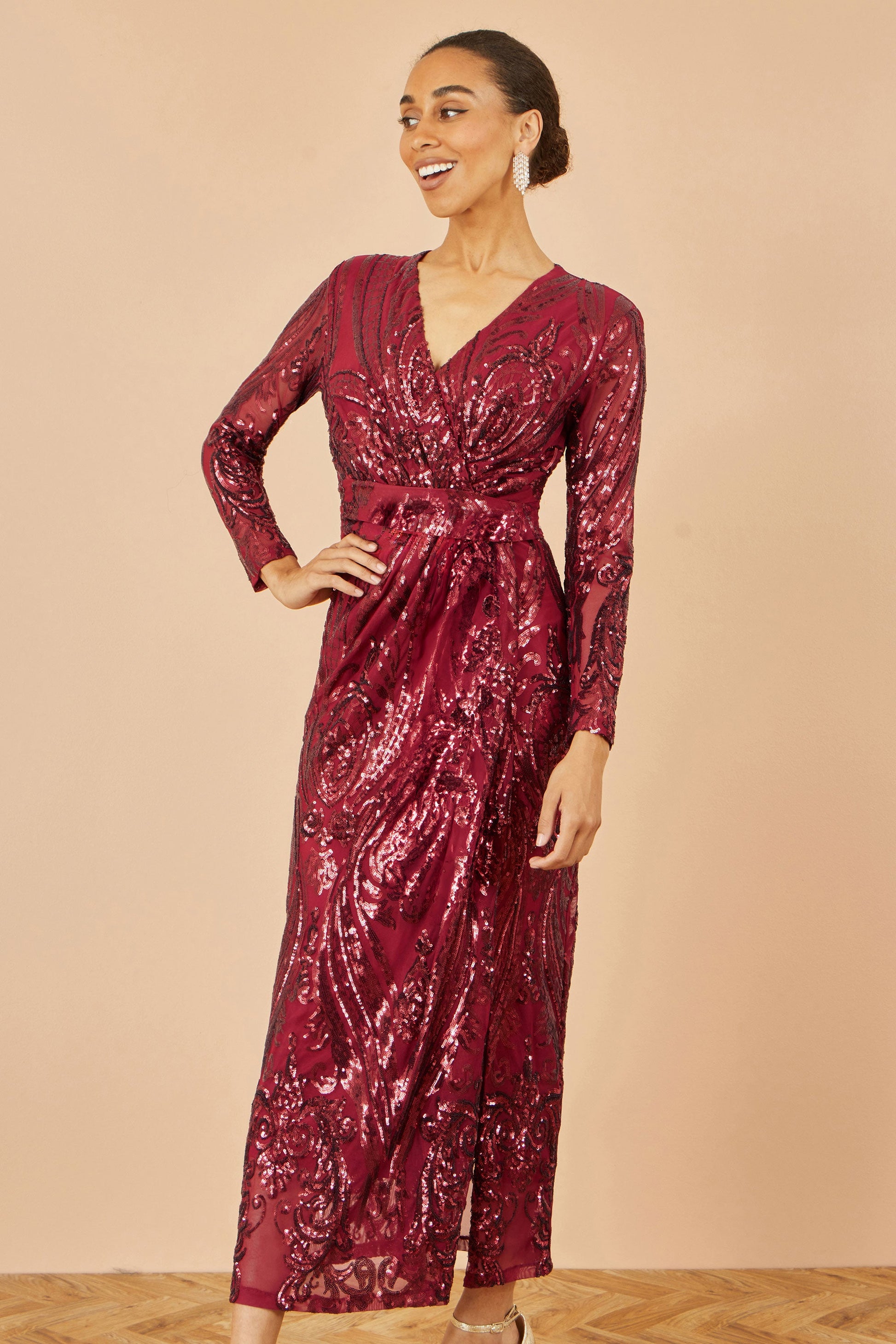 Woman wearing a burgundy sequin dress against a beige background