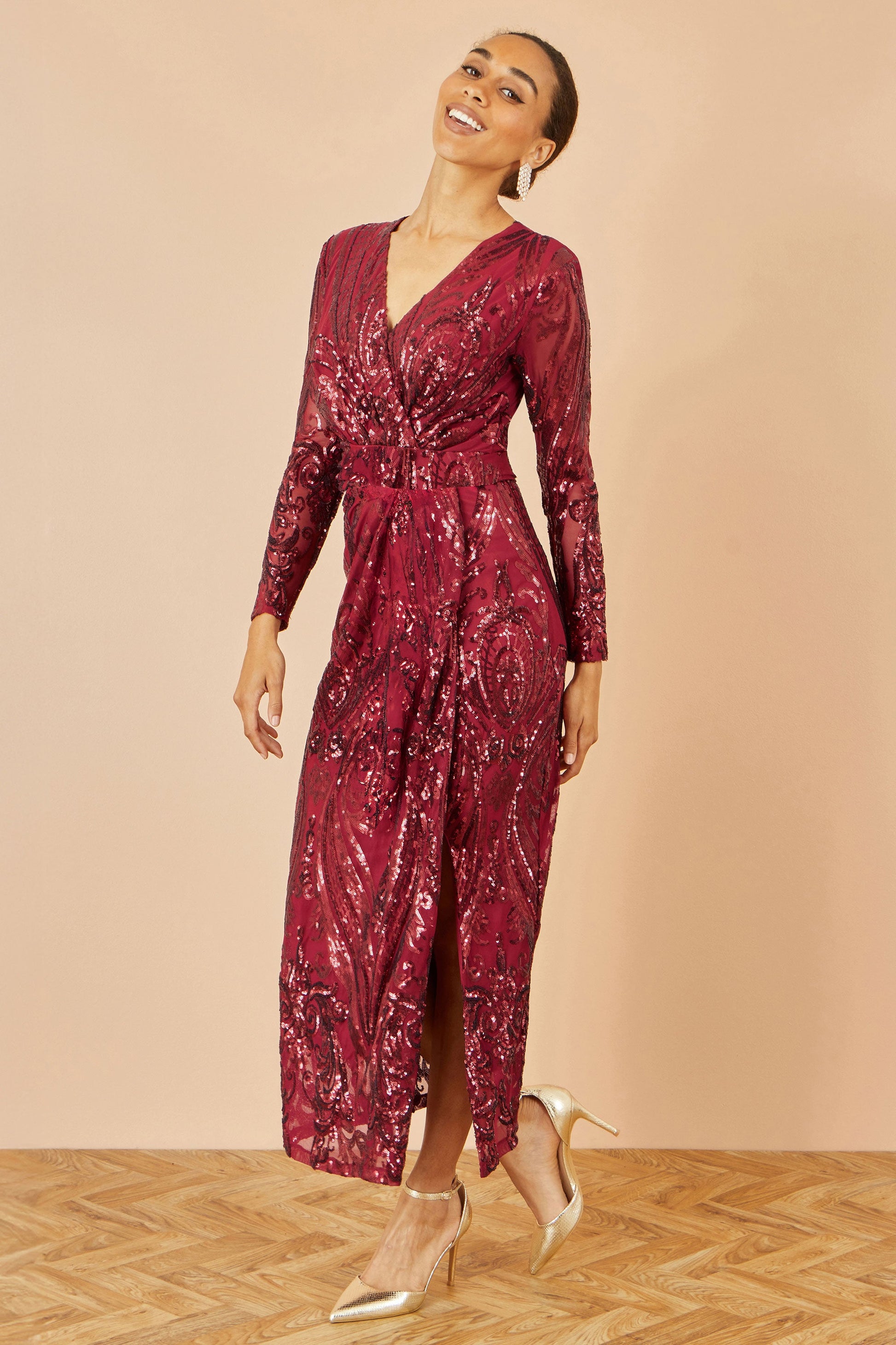 Woman wearing a burgundy sequin dress against a beige background