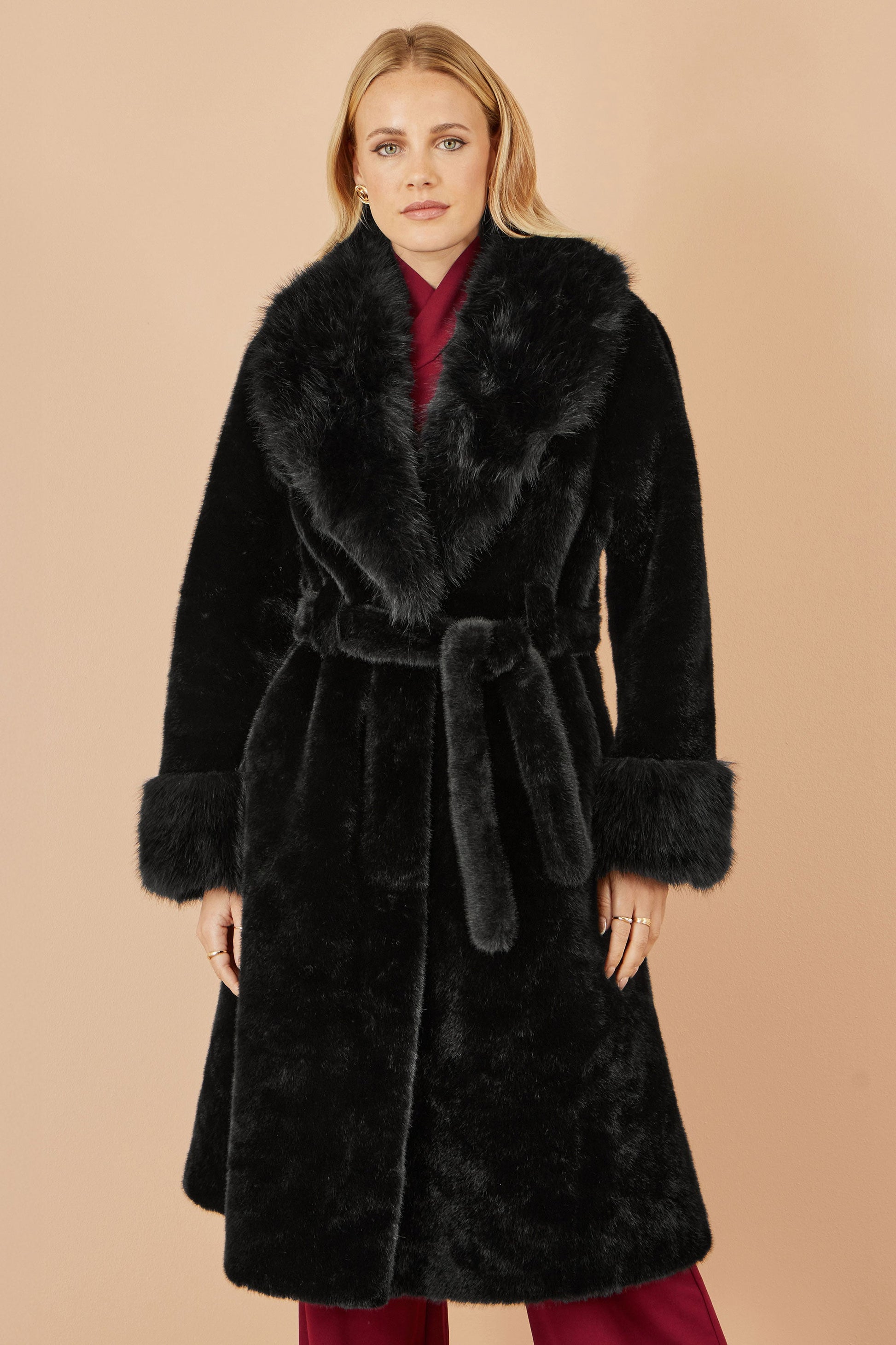 Woman wearing a black fur coat with a beige background