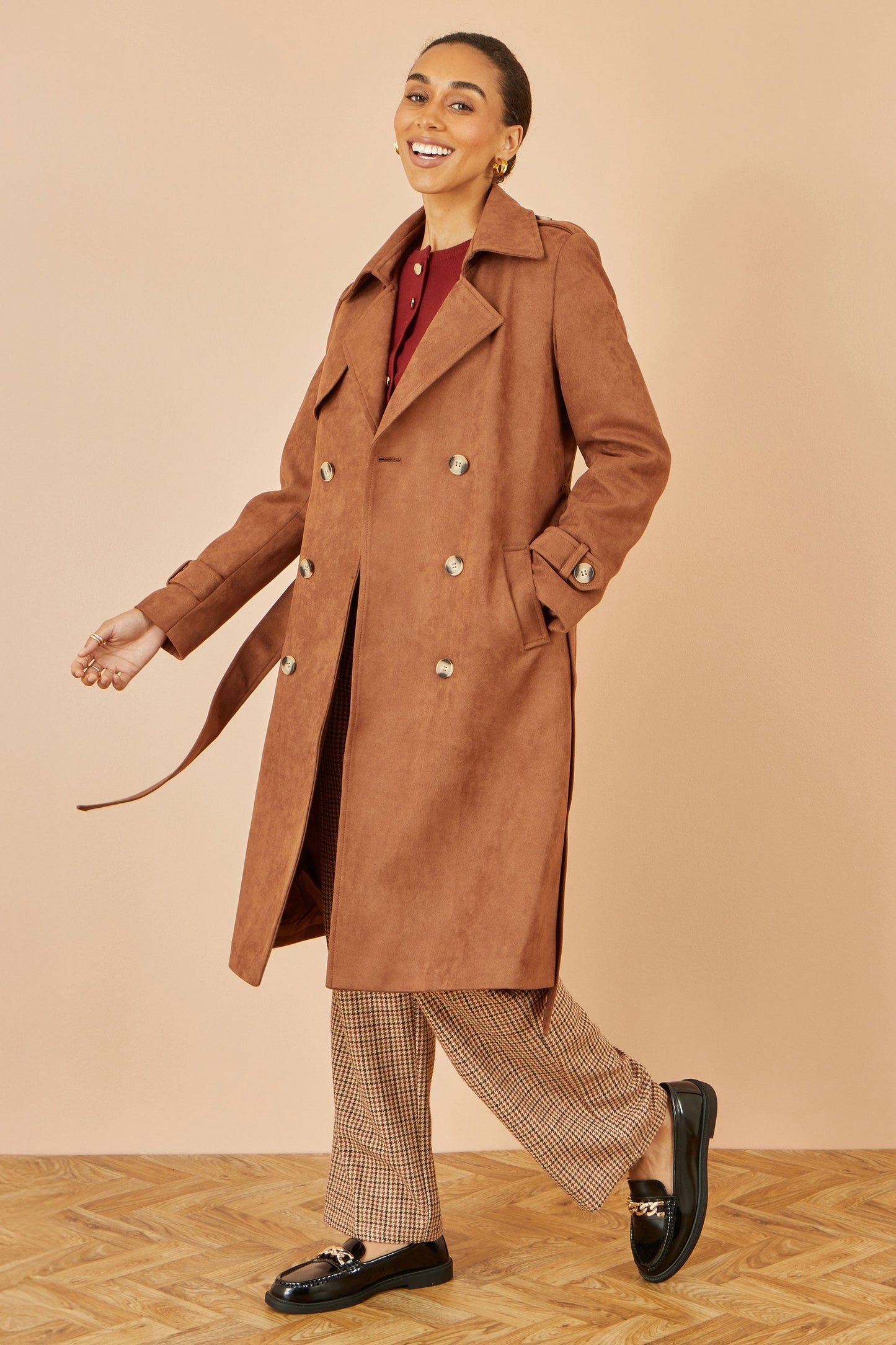 Woman wearing a brown coat with a plain background