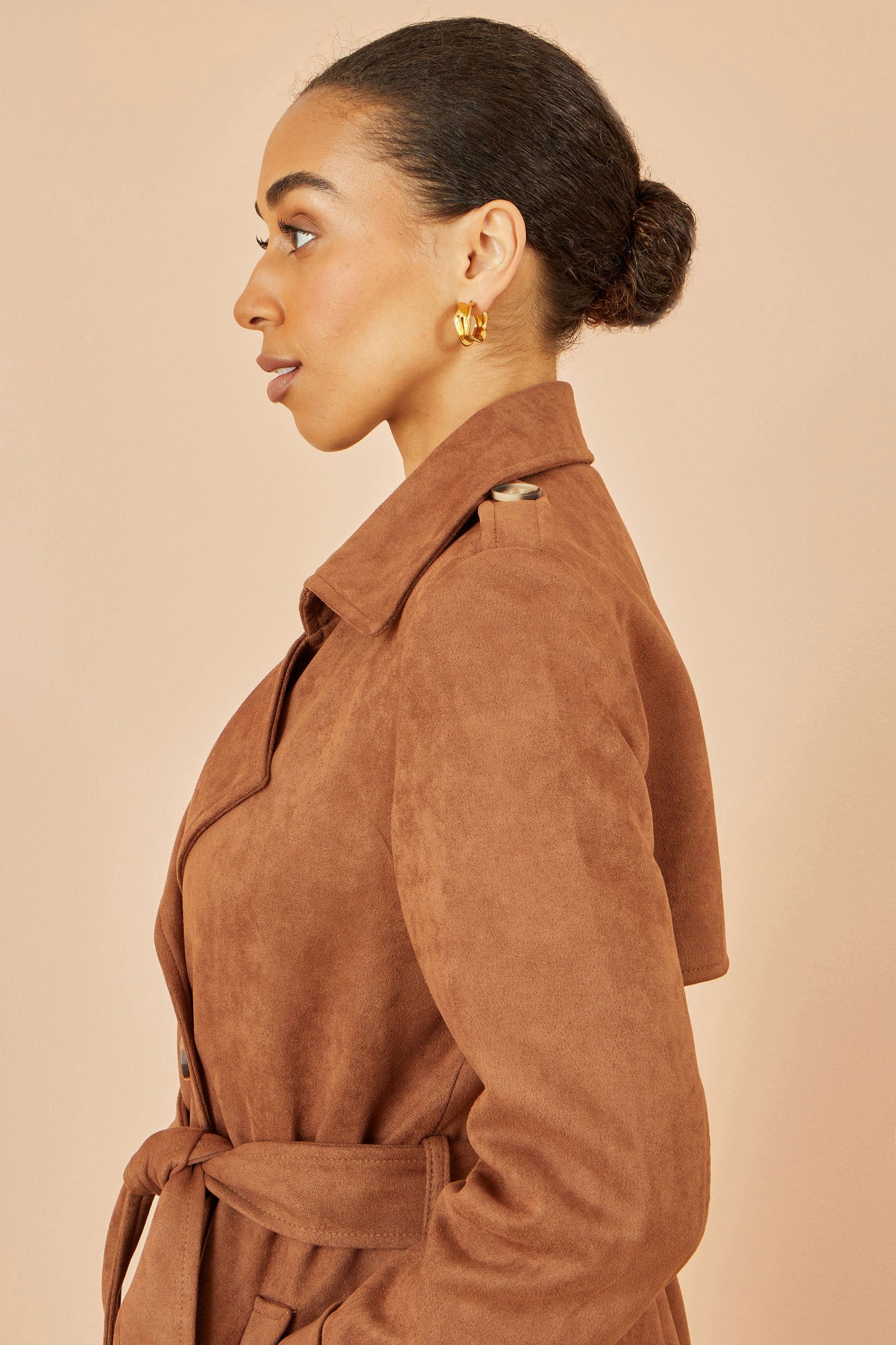 Woman wearing a brown coat against a beige background