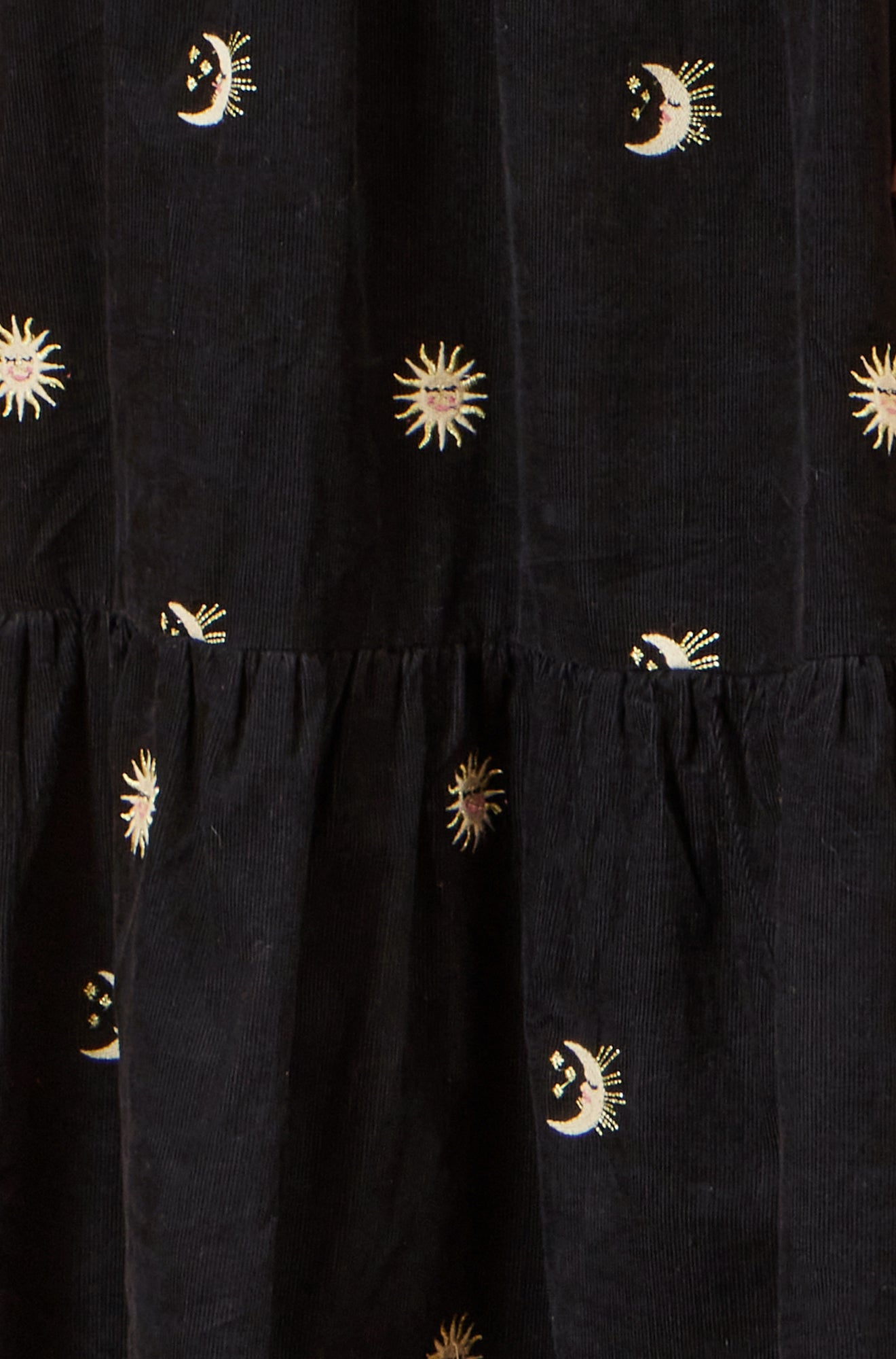 Black dress with embroidered sun and moon patterns on a black background