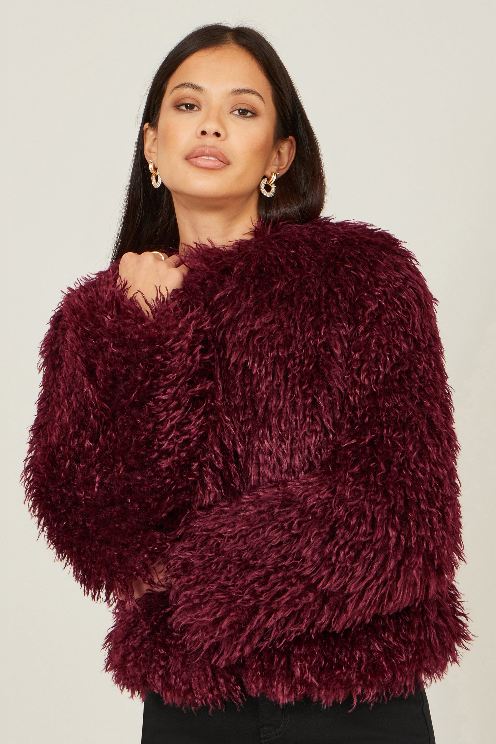 Woman wearing a fluffy burgundy sweater against a plain background