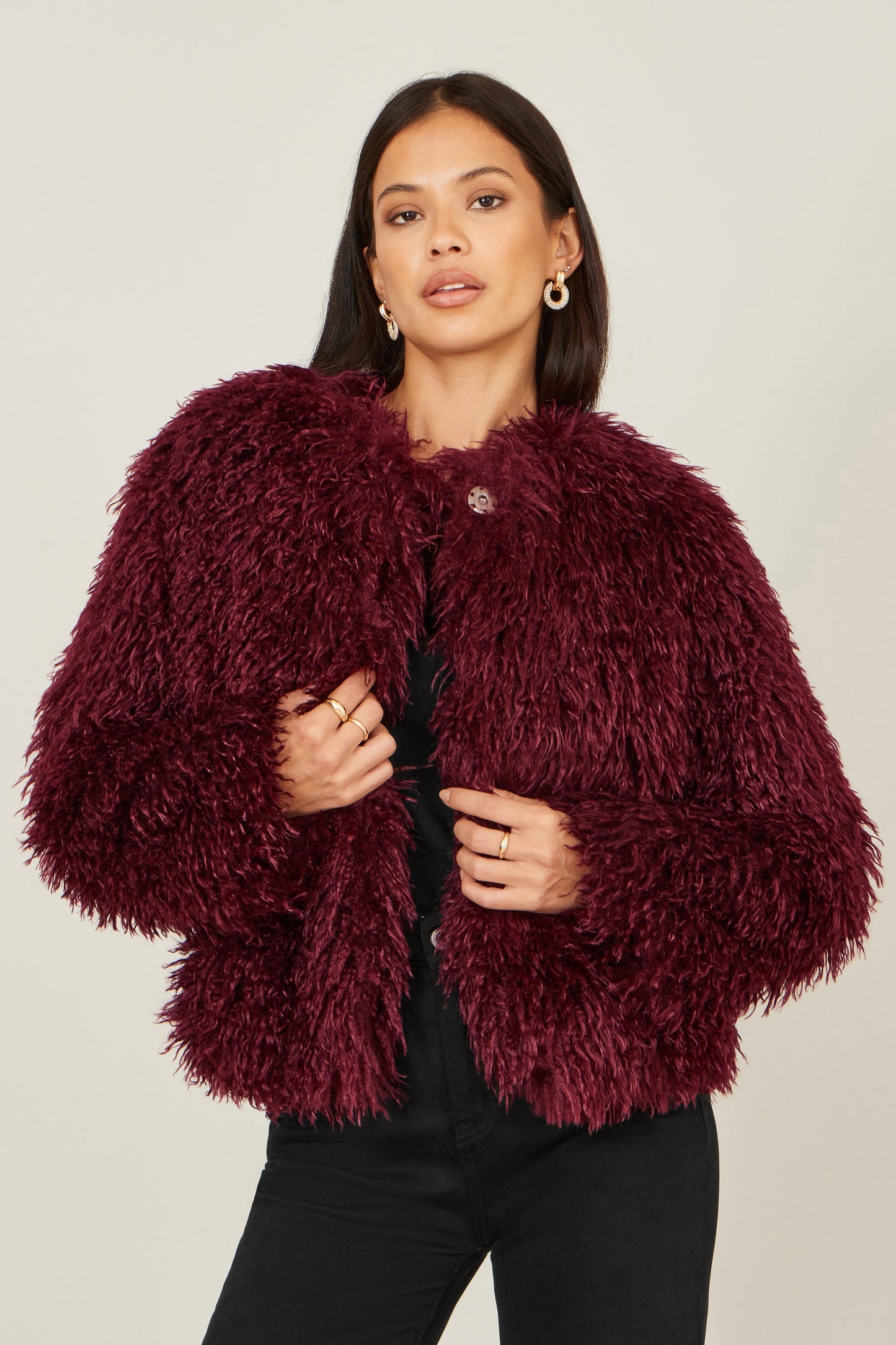 Woman wearing a burgundy fluffy jacket on a plain background