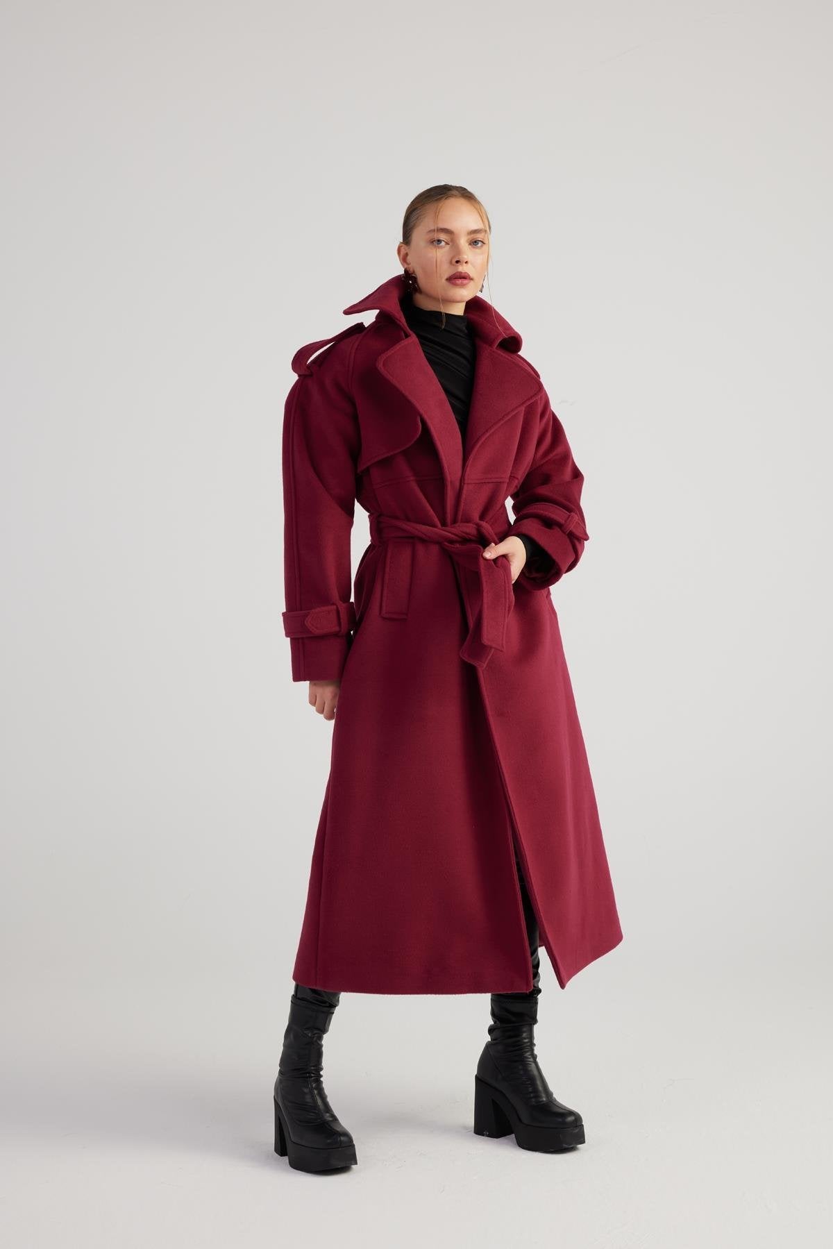 Woman wearing a long burgundy coat on a white background
