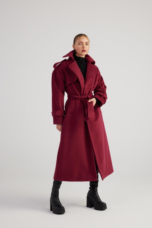 Woman wearing a long burgundy coat on a white background
