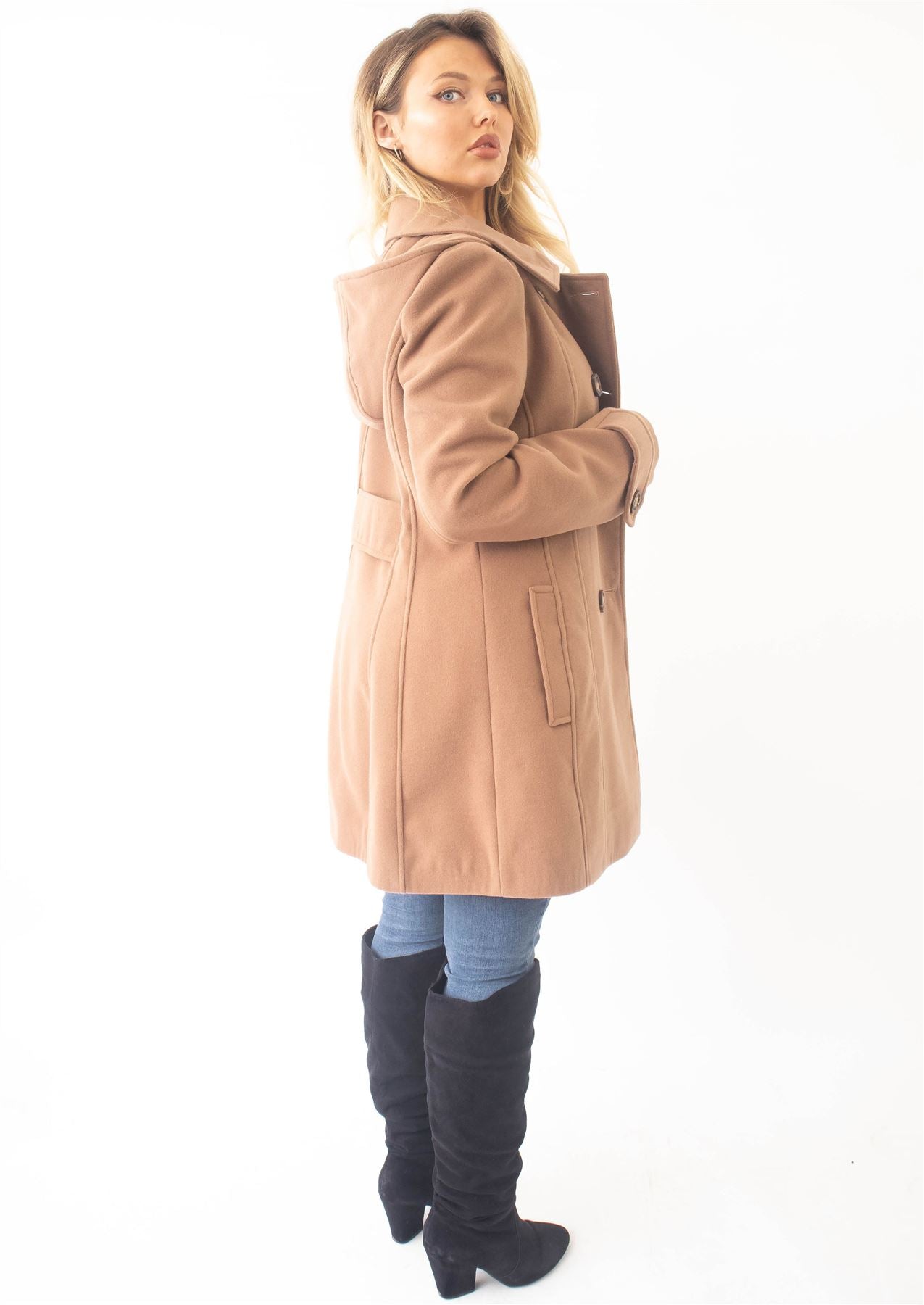 Woman wearing a beige coat and knee-high boots on a white background