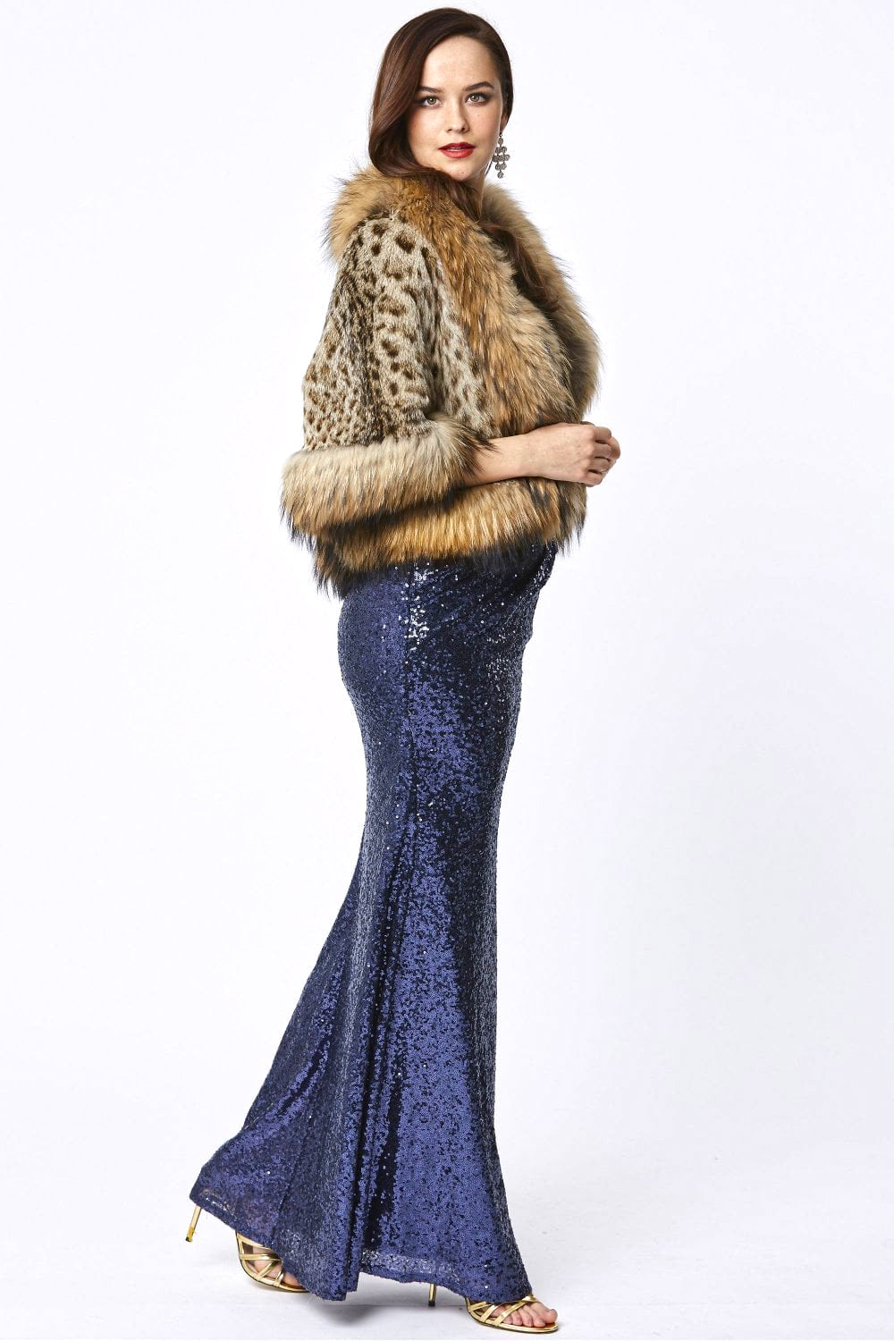 Woman wearing a fur coat and blue sequin dress on a white background