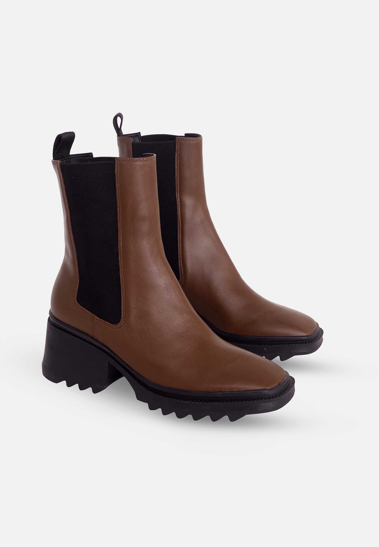 Pair of brown Chelsea boots with black soles on a white background