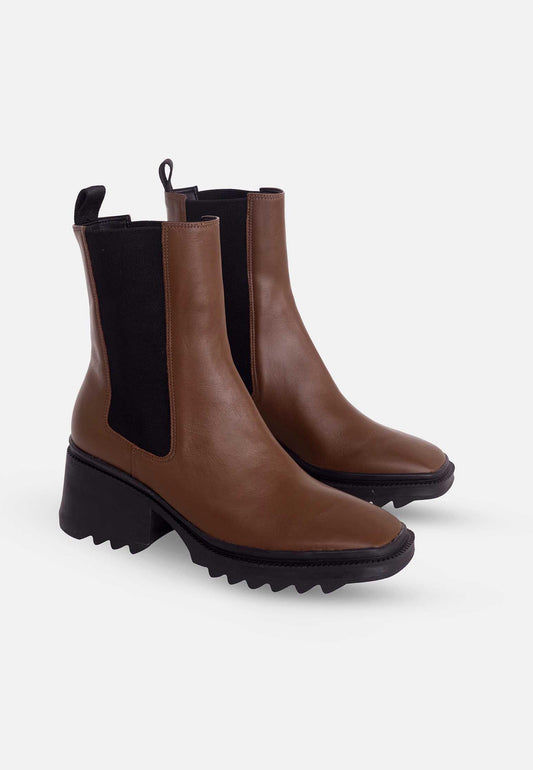 Pair of brown Chelsea boots with black soles on a white background