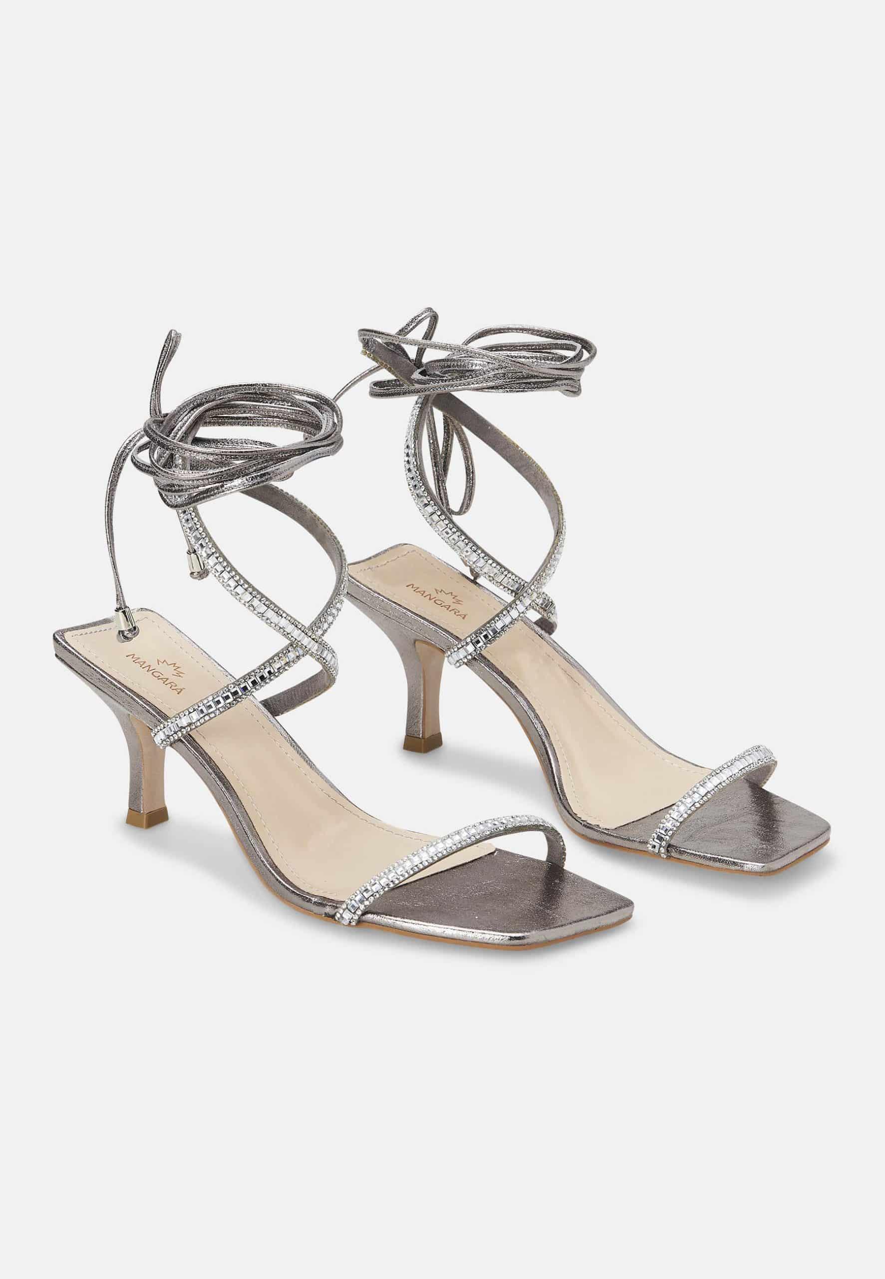 Pair of silver high-heeled sandals with strappy design on a white background