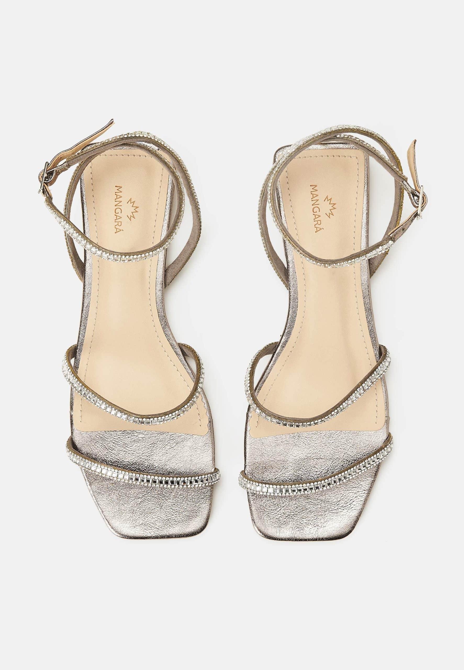 Pair of silver high-heeled sandals with decorative straps on a white background