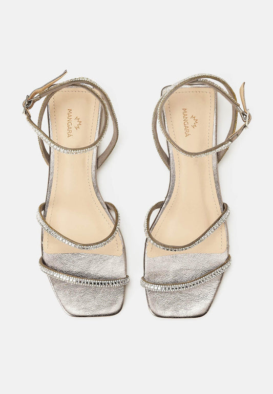 Pair of silver high-heeled sandals with decorative straps on a white background