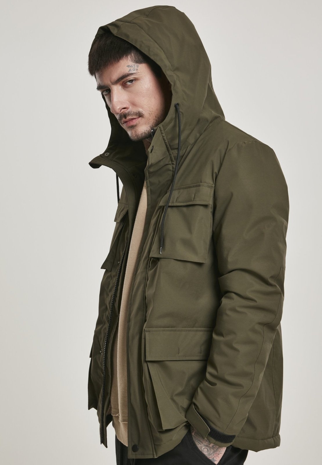 Man wearing a green hooded jacket against a plain background