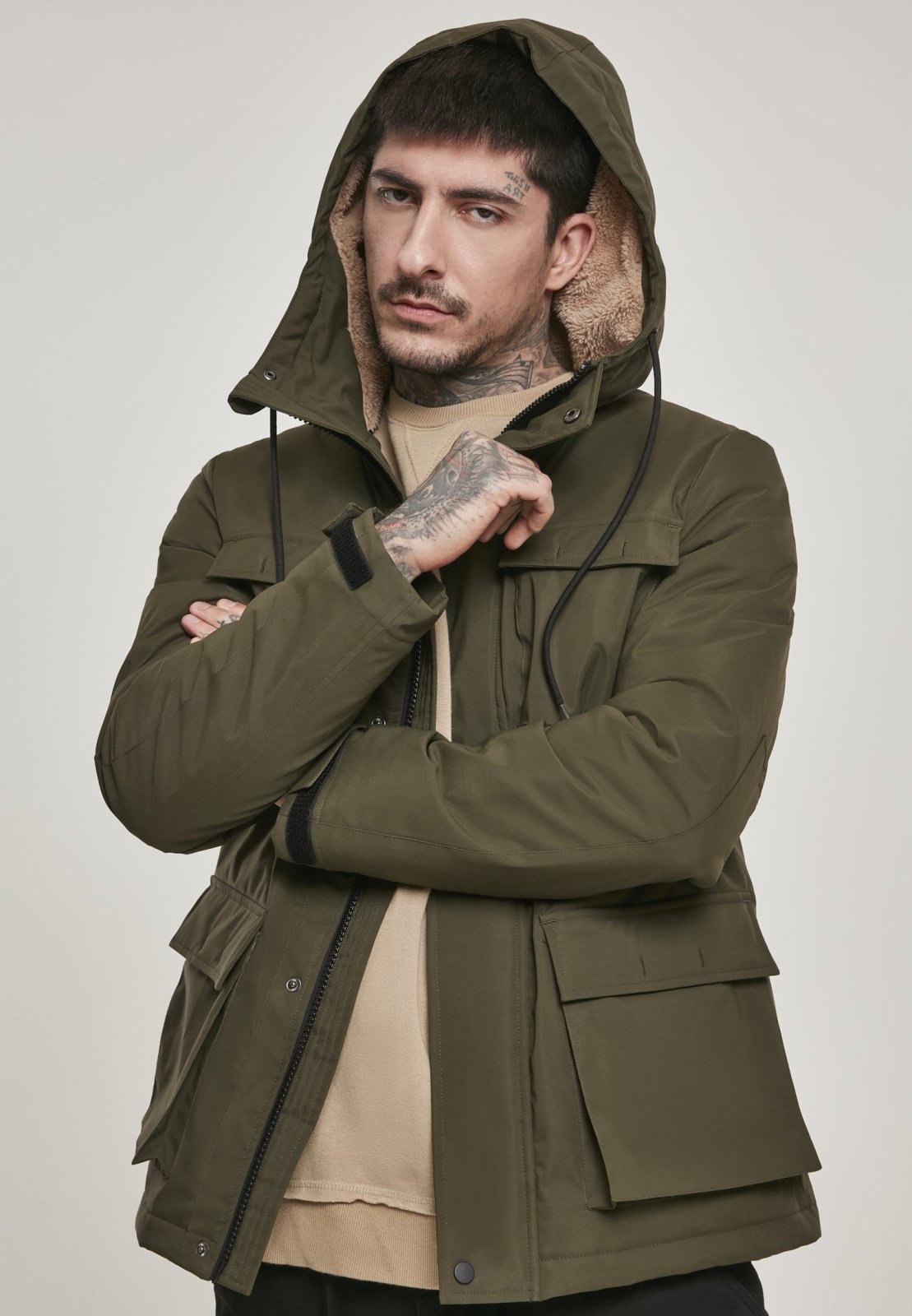 Man wearing a green hooded jacket against a plain background