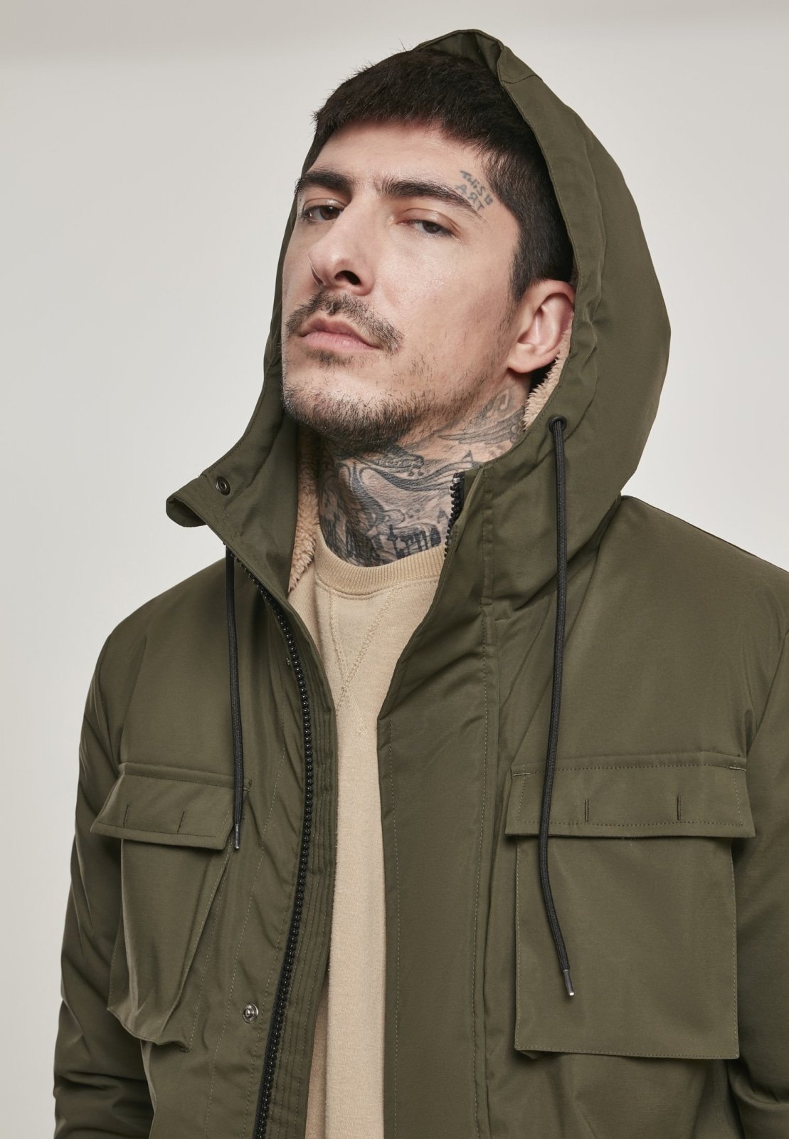 Man wearing a green hooded jacket against a plain background