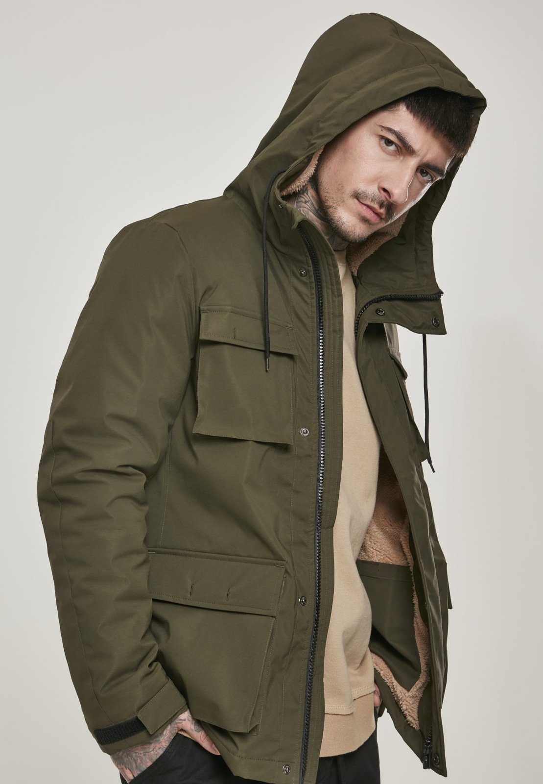 Man wearing a green hooded jacket on a plain background