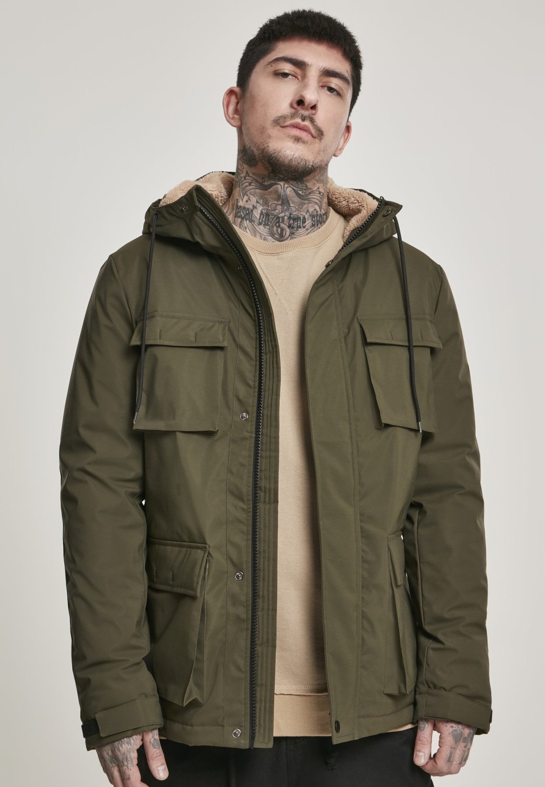 Man wearing a green parka jacket against a plain background