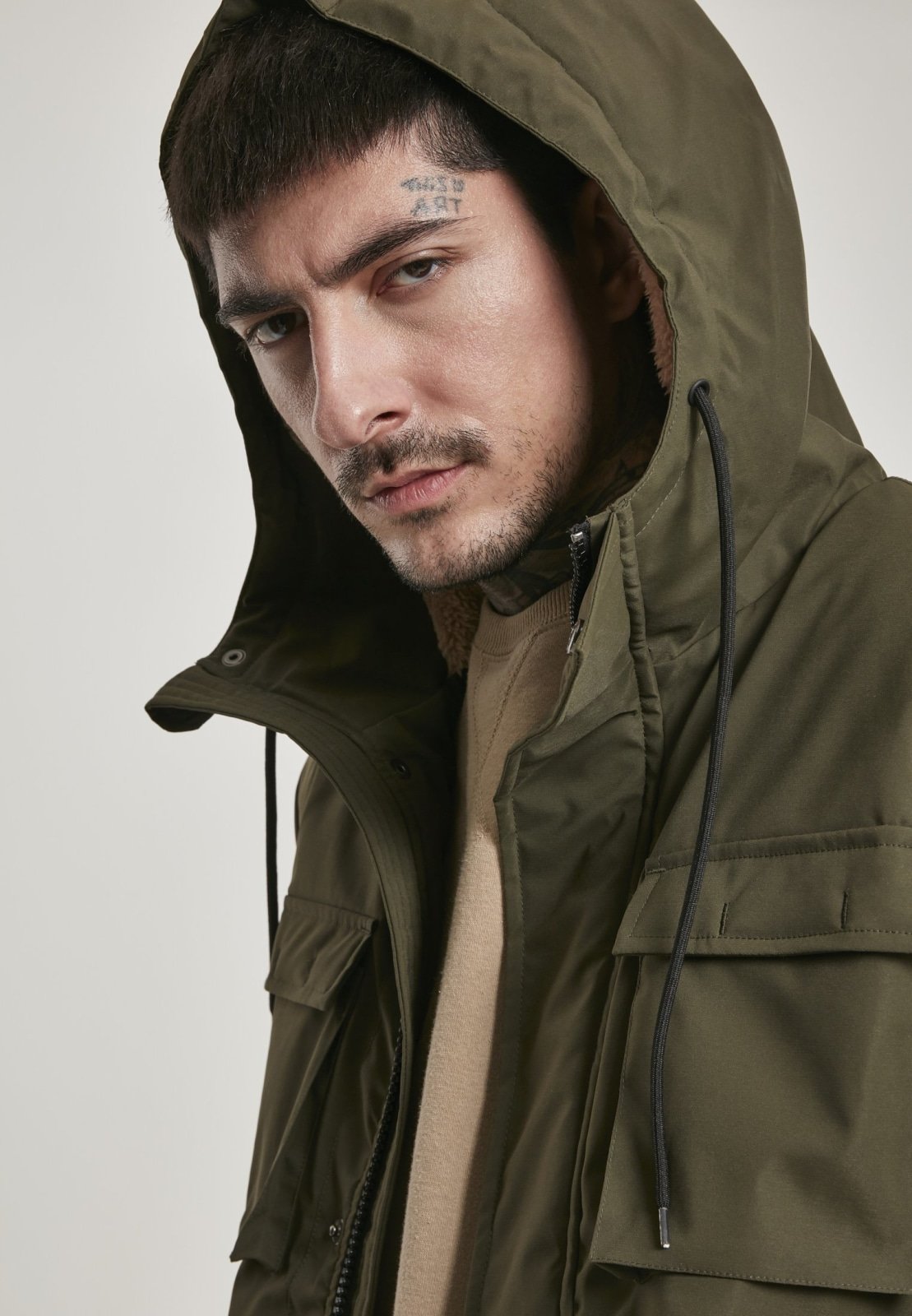 Man wearing a green hooded jacket against a plain background