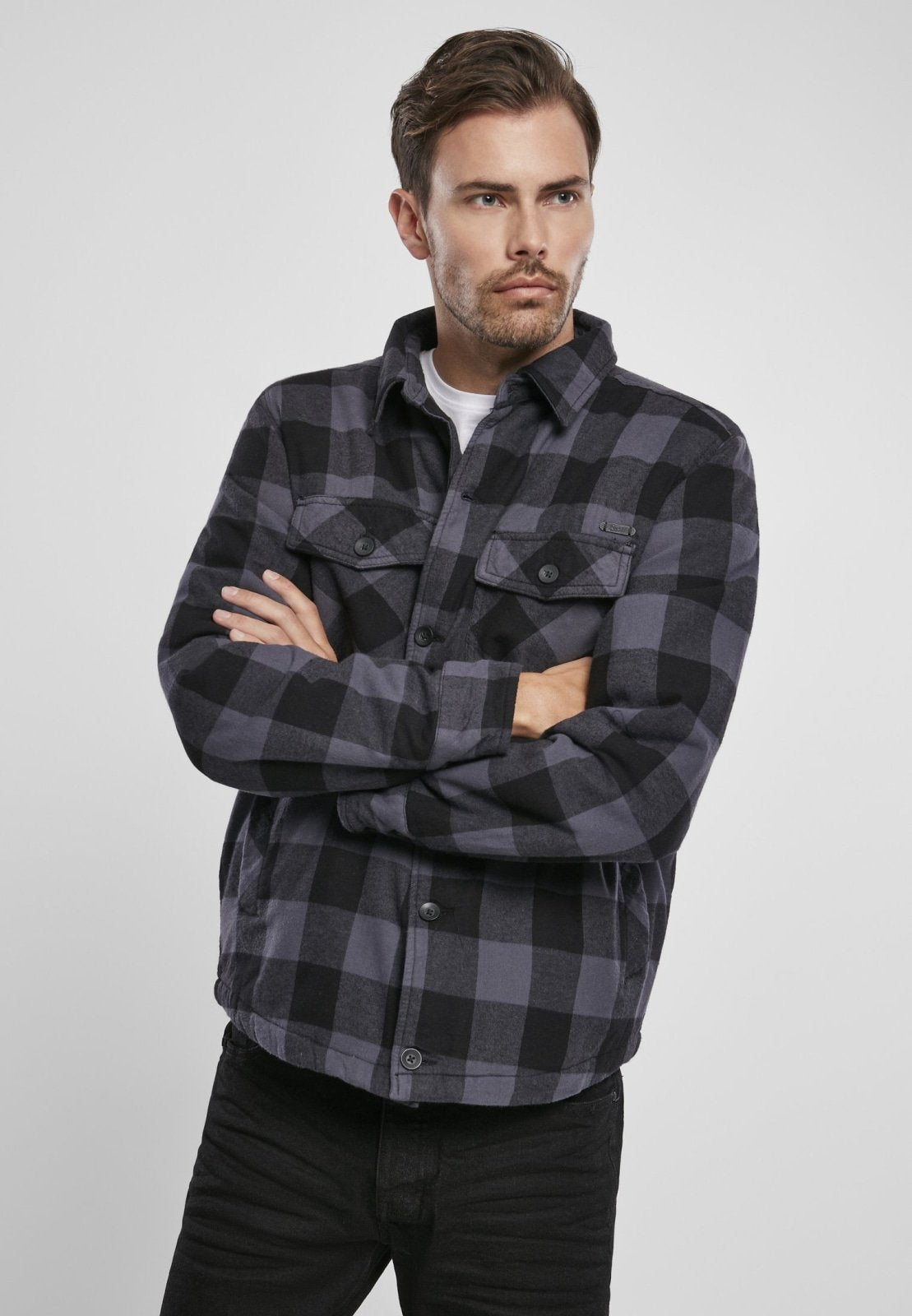 Man wearing a black and gray checkered shirt with a brand logo on a white background