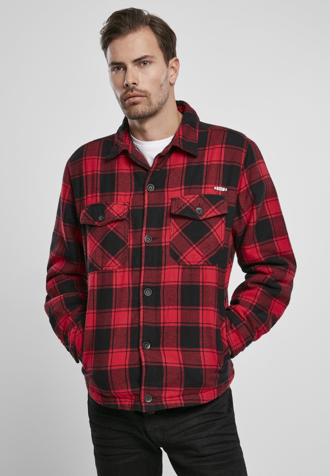 Man wearing a red and black plaid shirt on a gray background
