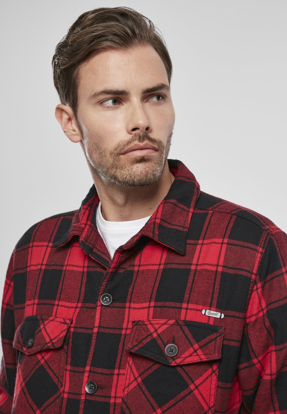 Man wearing a red and black plaid shirt against a plain background