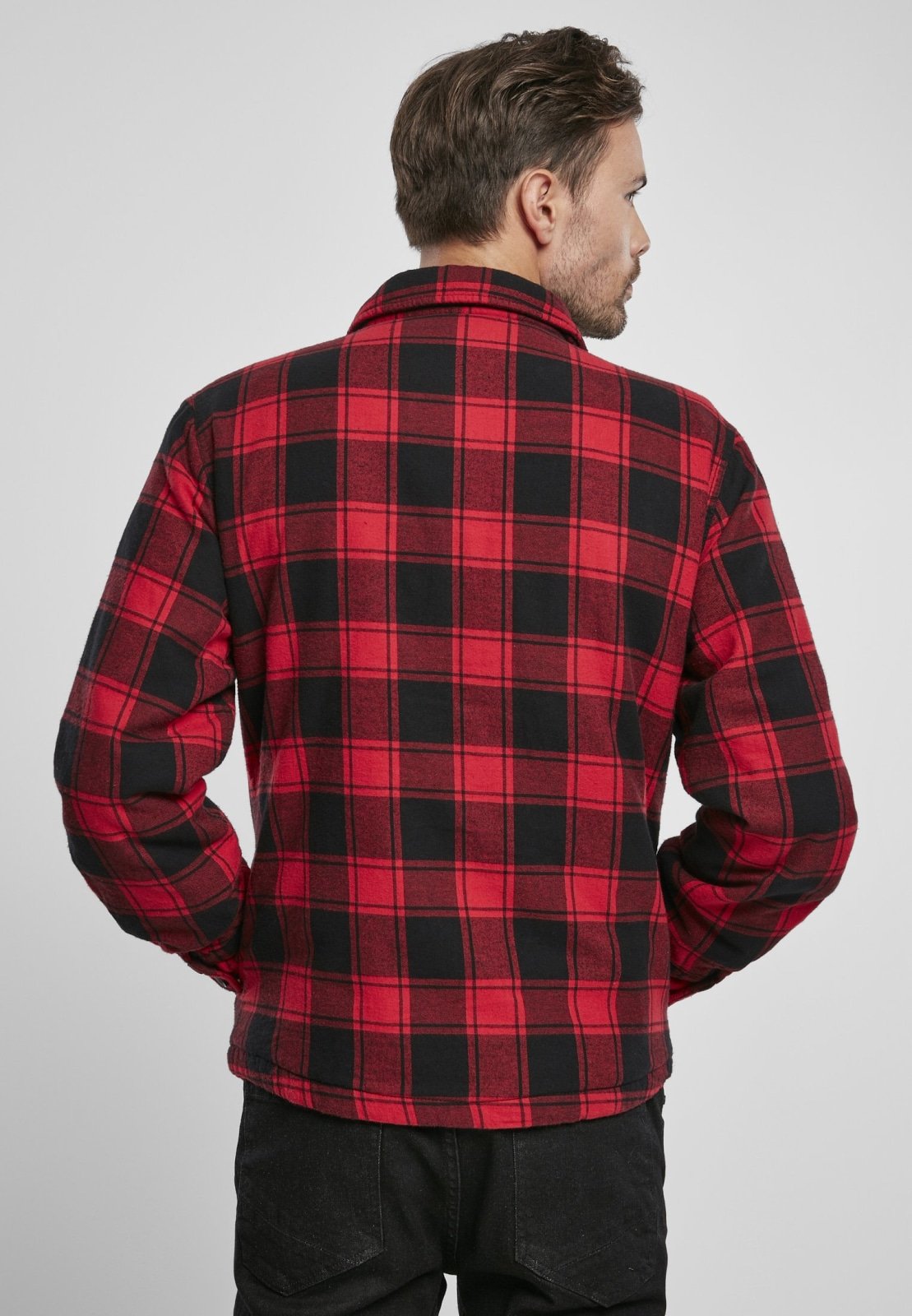Man wearing a red and black plaid shirt against a plain background